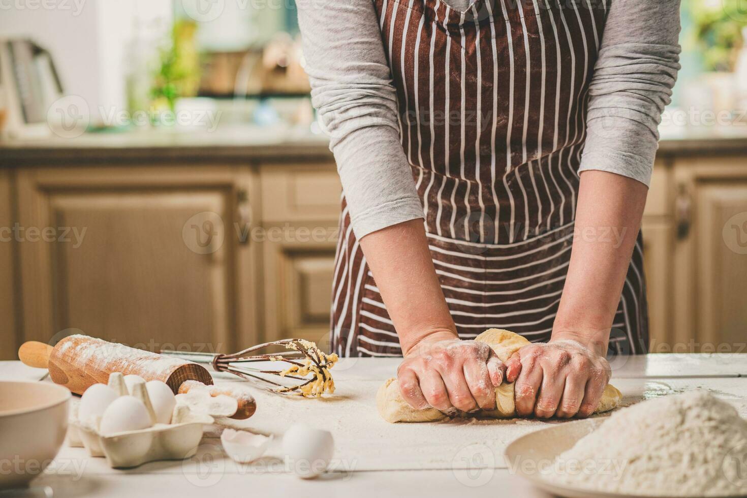 Woman hands kneading dough on kitchen table photo