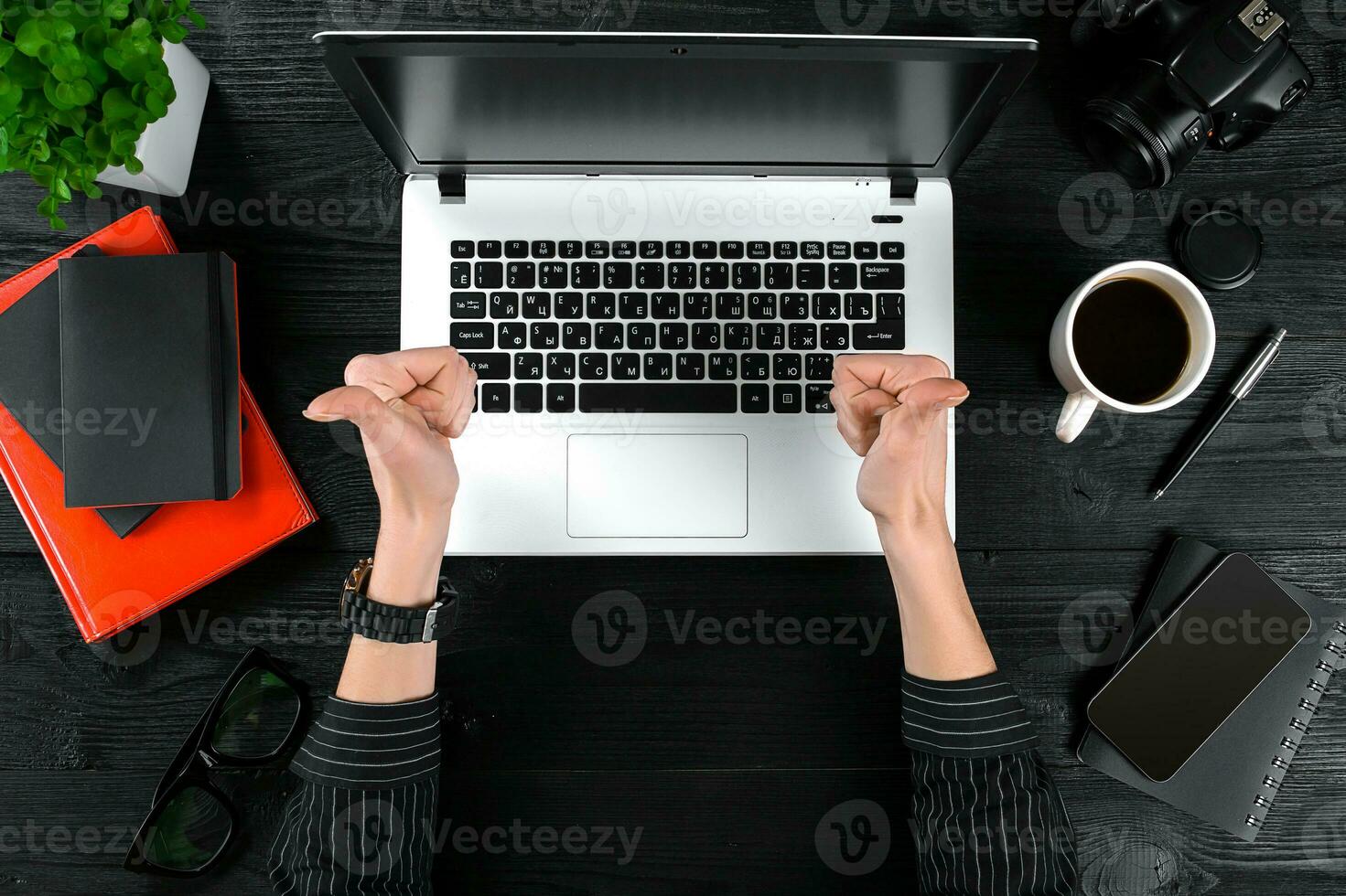 Woman working at the office table. Top view of human hands, laptop keyboard, a cup of coffee, smartphone, notebook and a flower on a wooden table background photo
