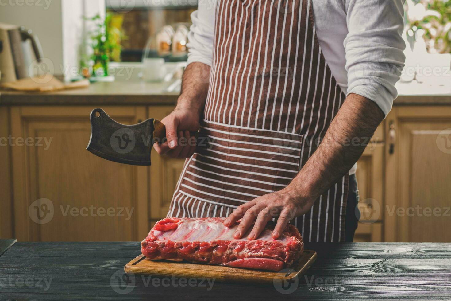 Man cuts of fresh piece of beef on a wooden cutting board in the home kitchen photo