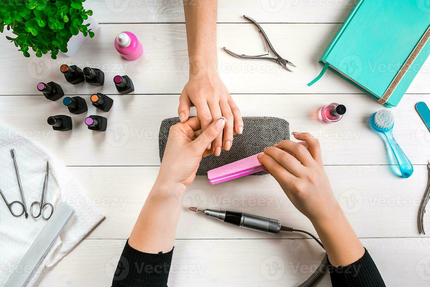 Closeup shot of a woman in a nail salon receiving a manicure by a beautician with nail file. Woman getting nail manicure. photo
