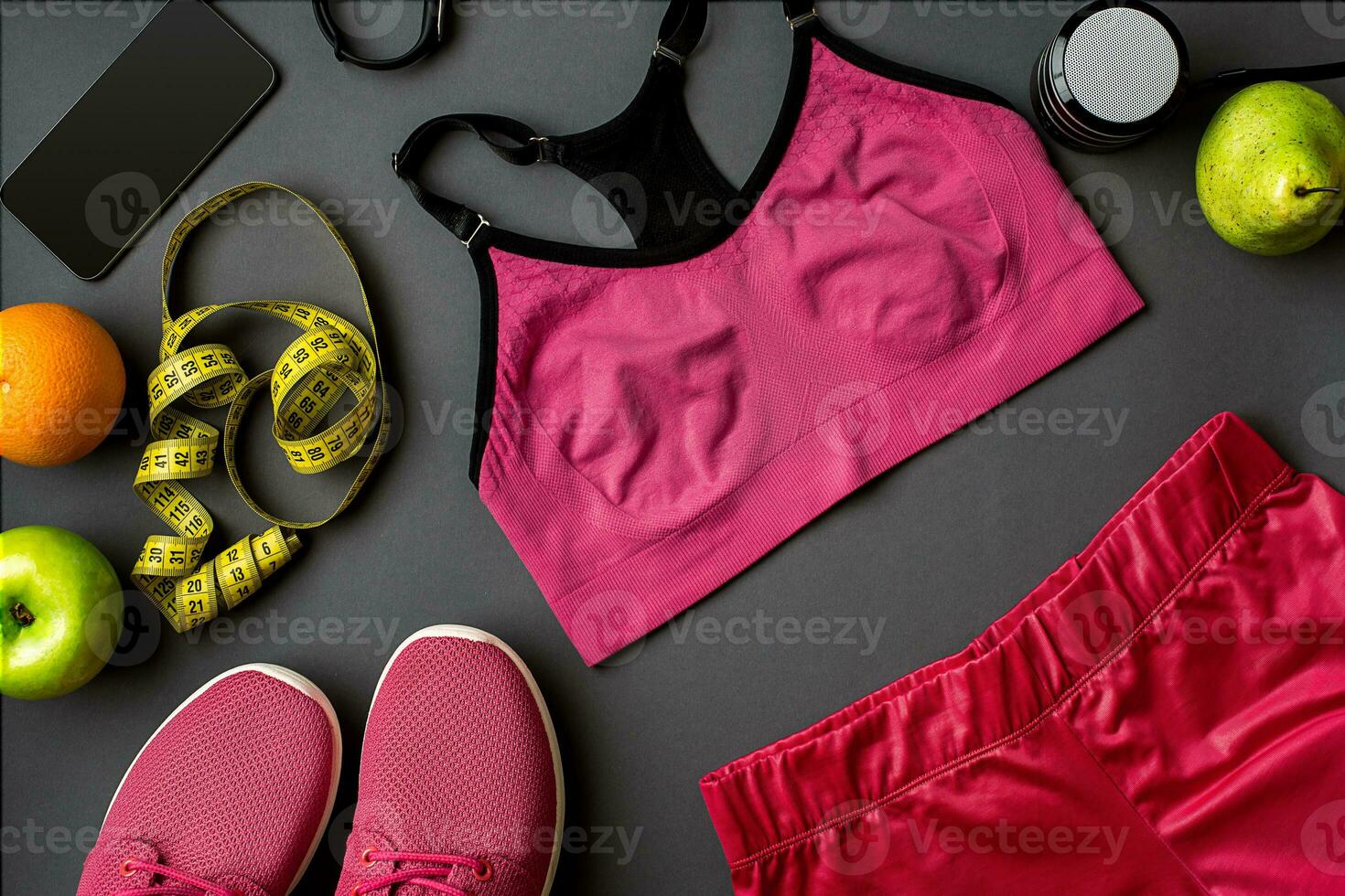 Athlete's set with female clothing, sneakers and bottle of water on gray background photo