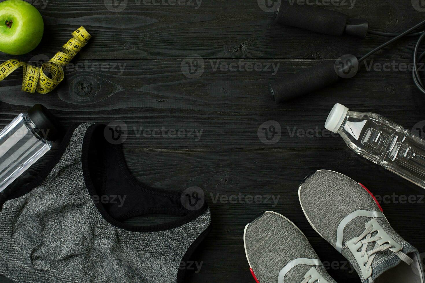 Athlete's set with female clothing, sneakers and bottle of water on dark background photo