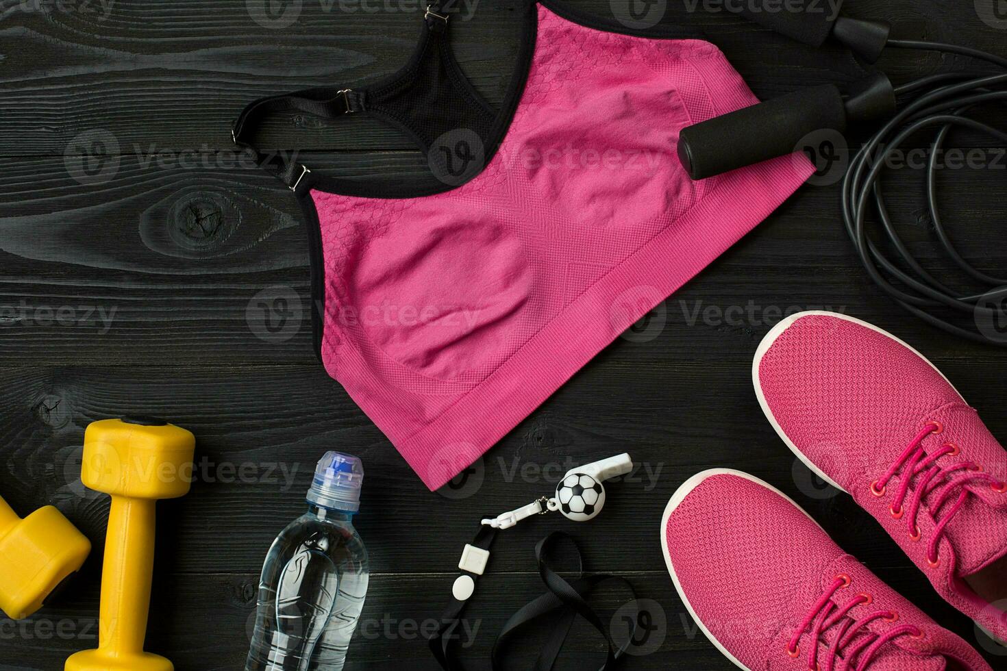 Athlete's set with female clothing, sneakers and bottle of water on dark background photo