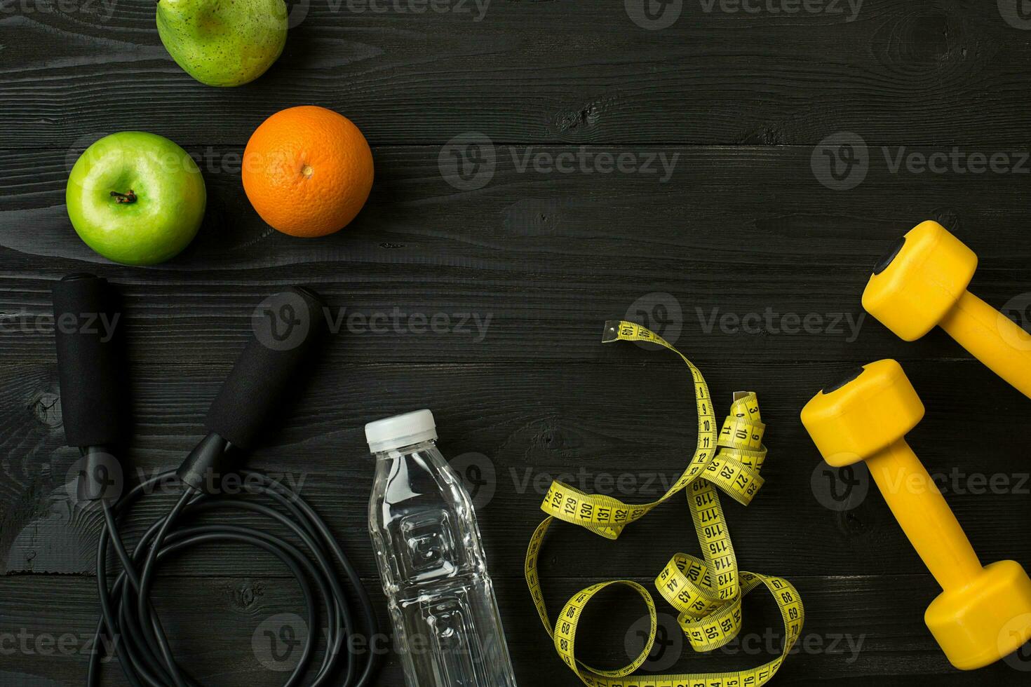 Athlete's set with female clothing, sneakers and bottle of water on dark background photo