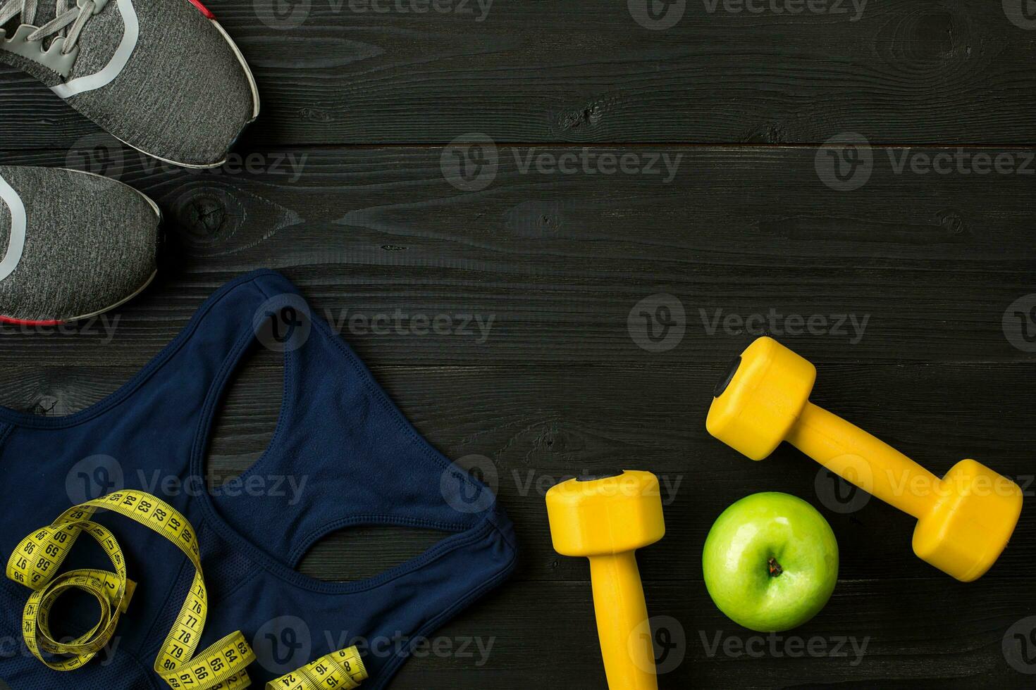 Athlete's set with female clothing, sneakers and bottle of water on dark background photo