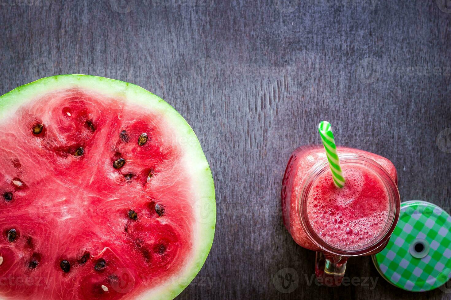 Watermelon smoothie and a half of fresh watermelon on dark wooden background. Flat lay or top view. photo