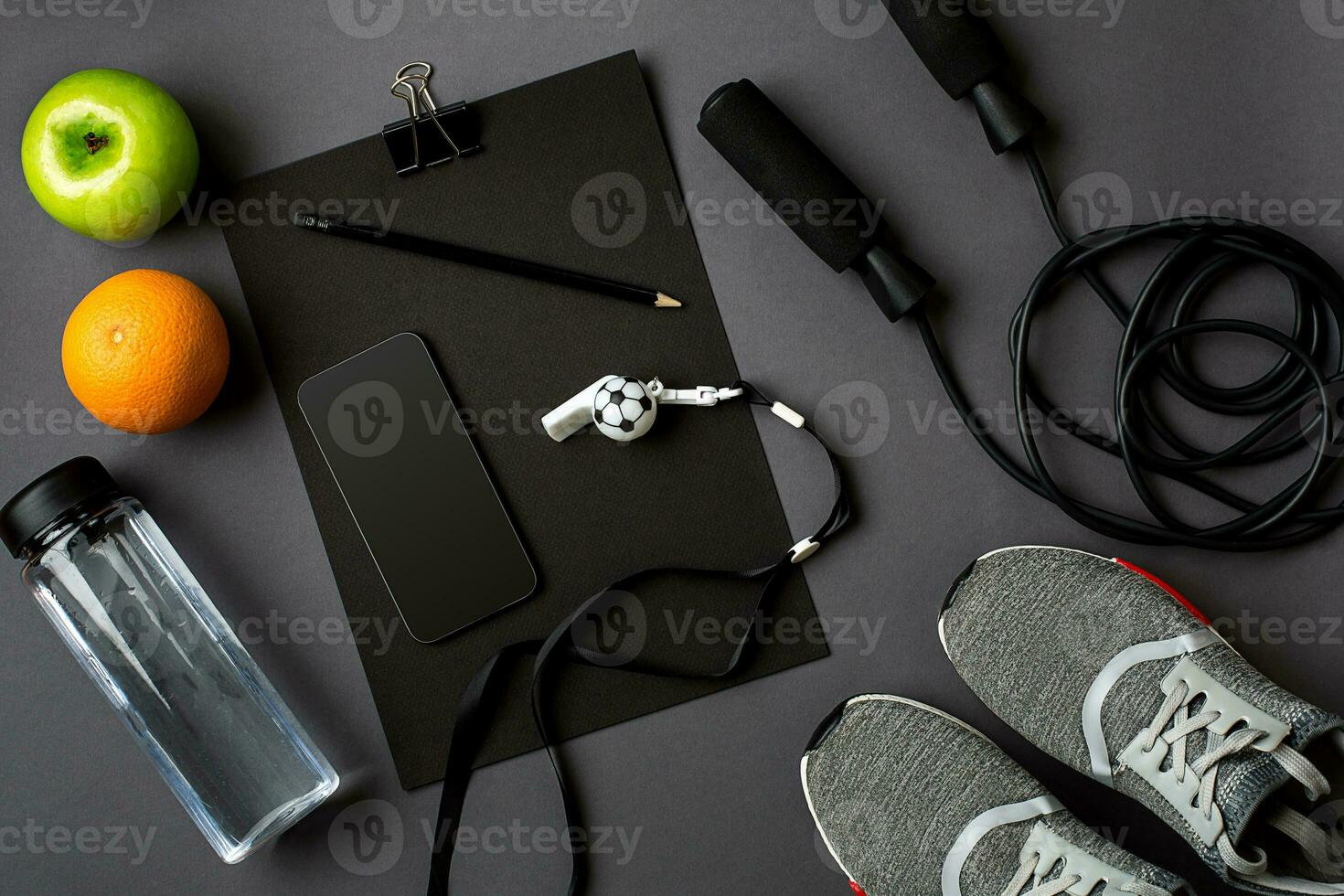 Athlete's set with female clothing, sneakers and bottle of water on gray background photo