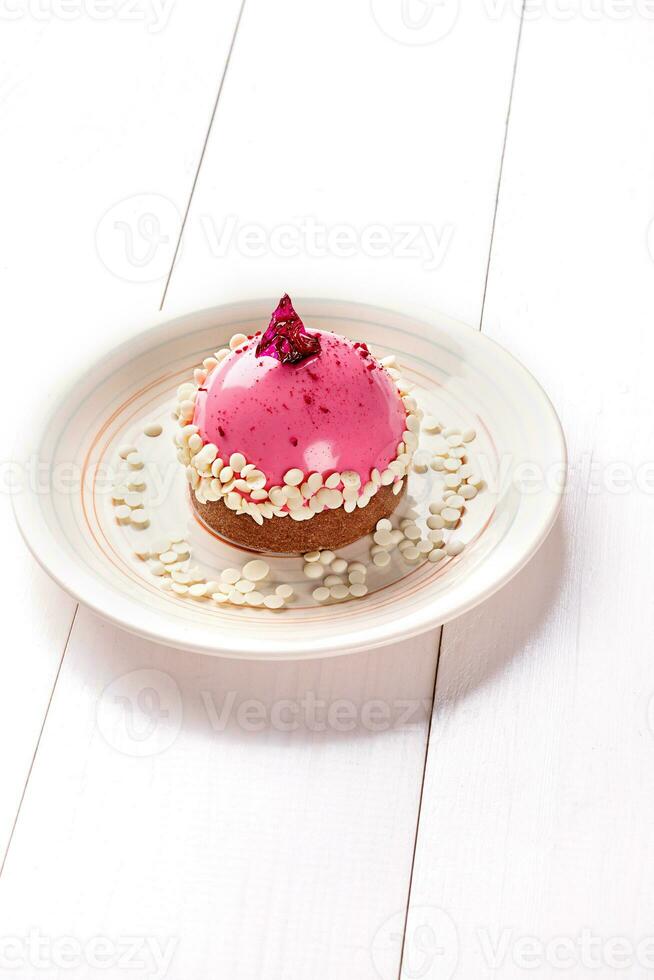 Small cake with different stuffing on a white plate. White wooden table. photo