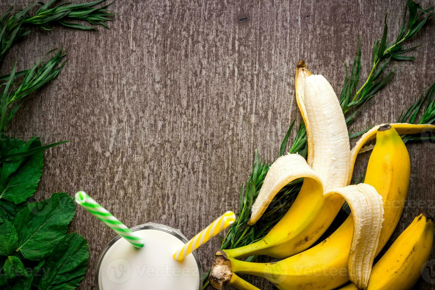 Banana smoothie and fresh banana on wooden table. photo