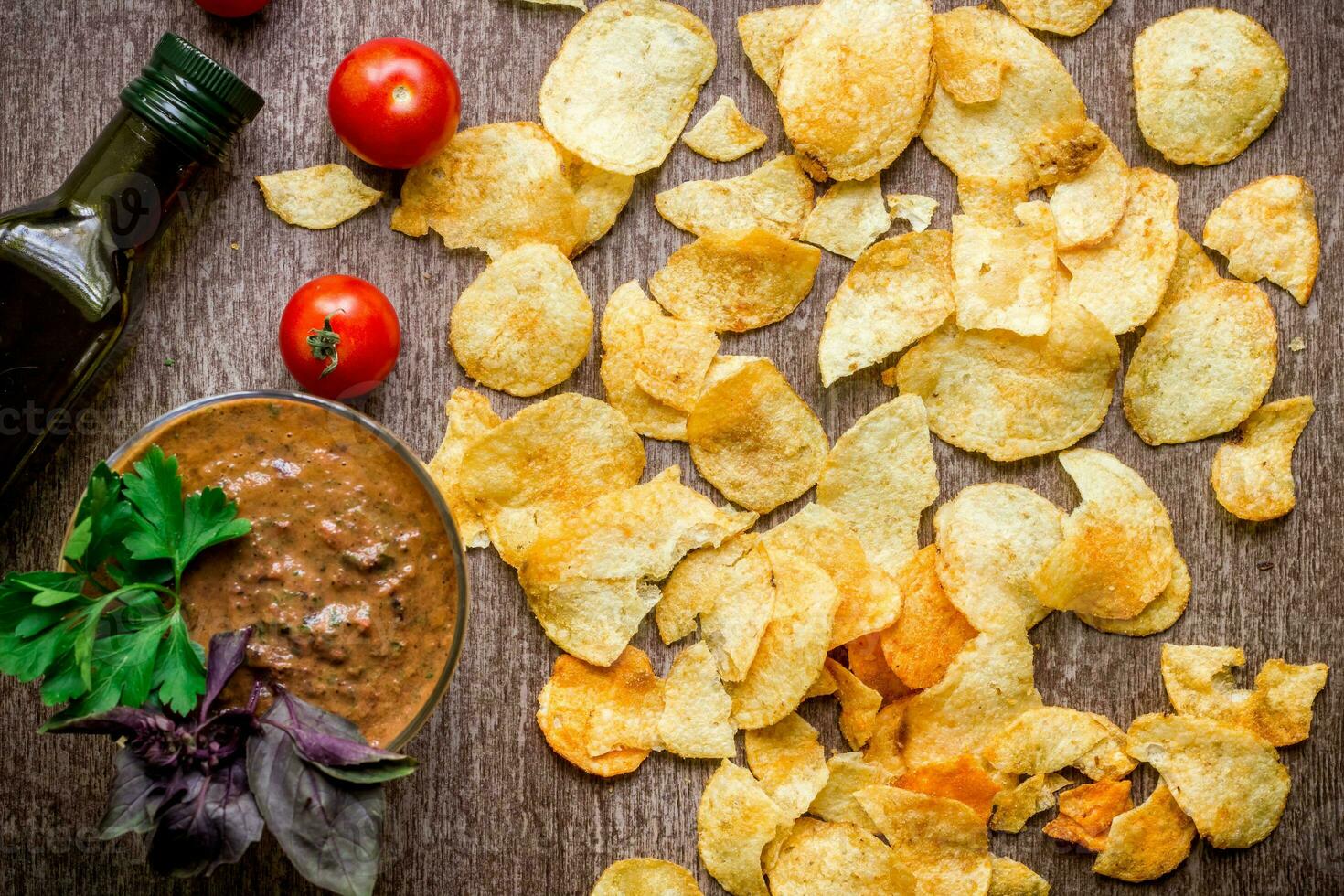 Potato chips with dipping sauce on a wooden table. Unhealthy food on a wooden background. photo