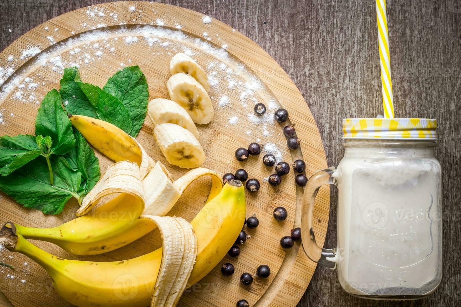 Banana smoothie and fresh banana on wooden table. photo