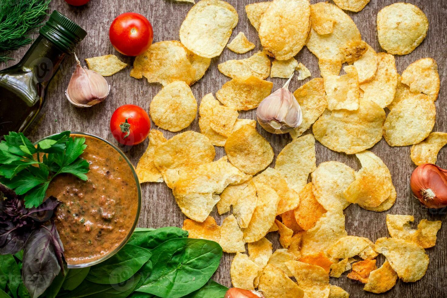 Potato chips with dipping sauce on a wooden table. Unhealthy food on a wooden background. photo