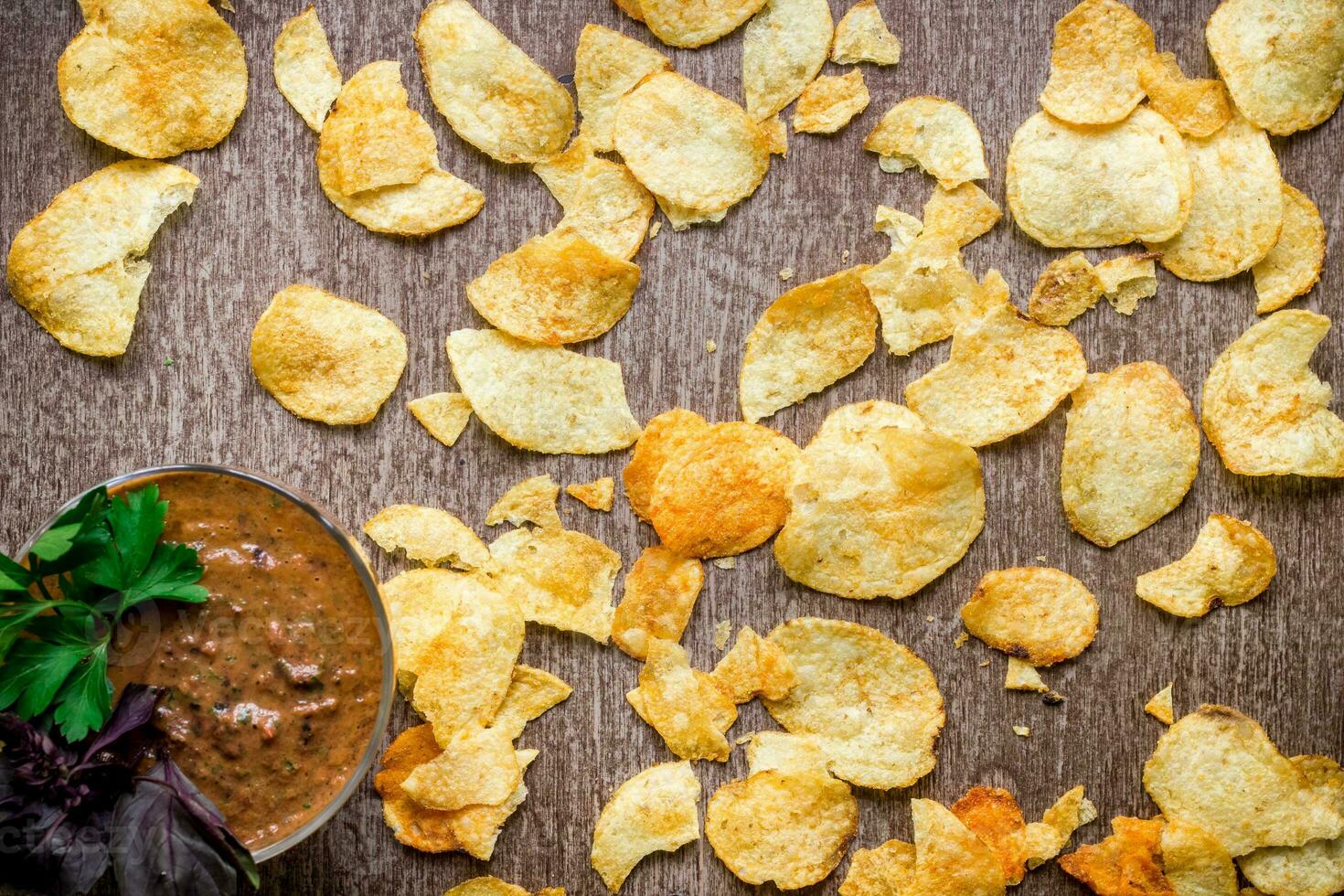 Potato chips with dipping sauce on a wooden table. Unhealthy food on a wooden background. photo