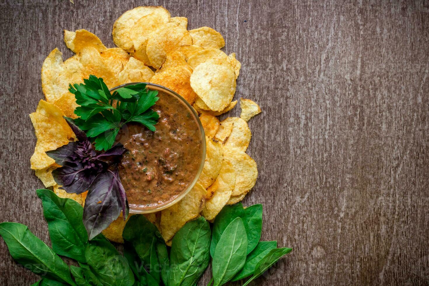 Potato chips with dipping sauce on a wooden table. Unhealthy food on a wooden background. photo