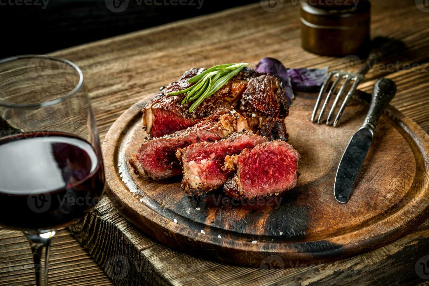 Grilled ribeye beef steak with red wine, herbs and spices on wooden table photo