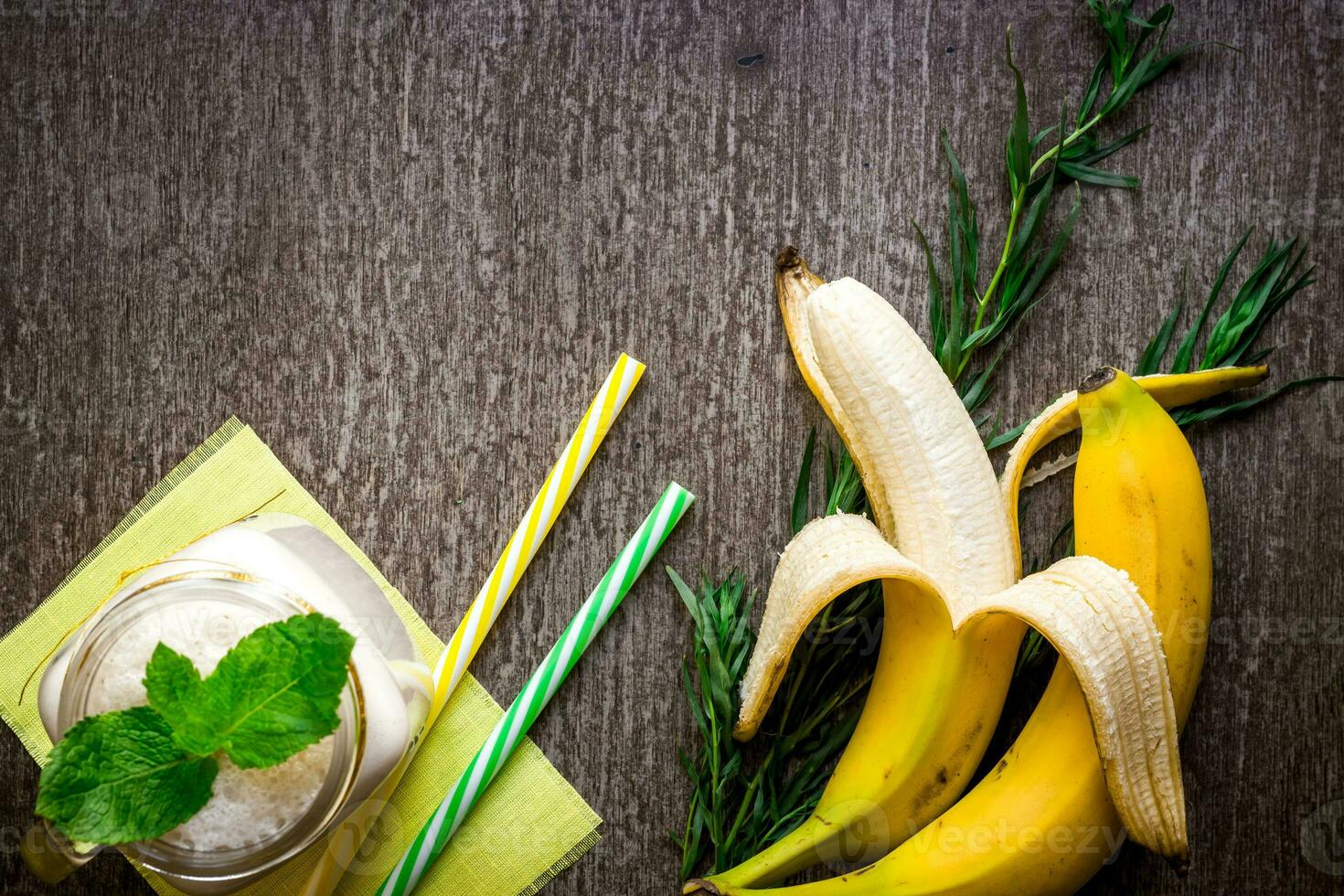 Banana smoothie and fresh banana on wooden table. photo