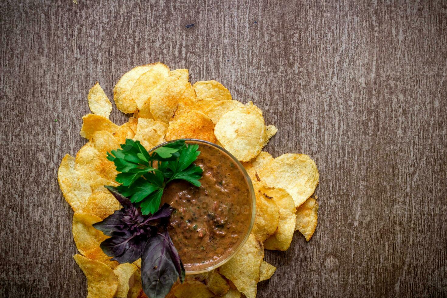 Potato chips with dipping sauce on a wooden table. Unhealthy food on a wooden background. photo