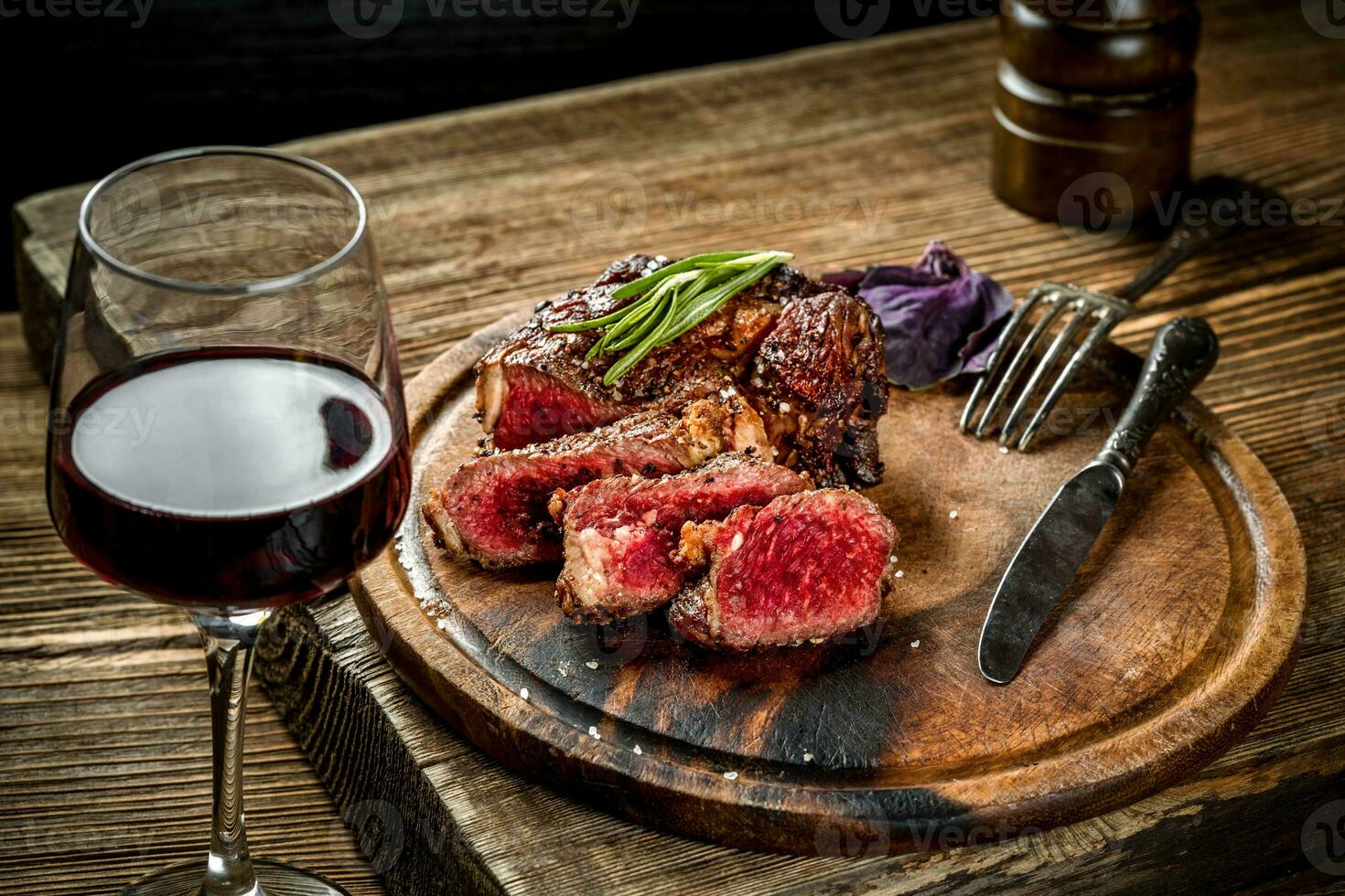 Grilled ribeye beef steak with red wine, herbs and spices on wooden table photo