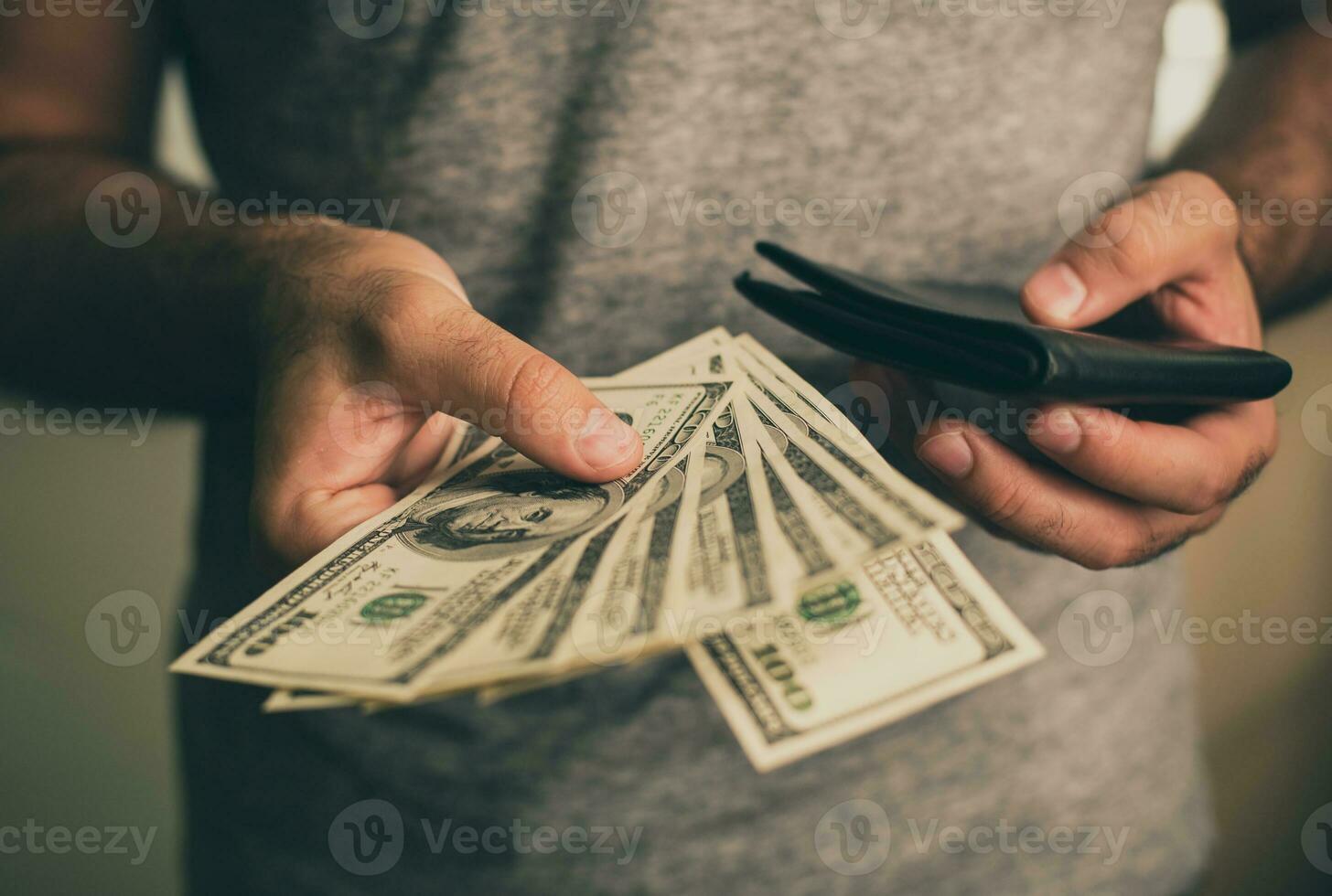 A man holds dollars and black wallet in his hands photo