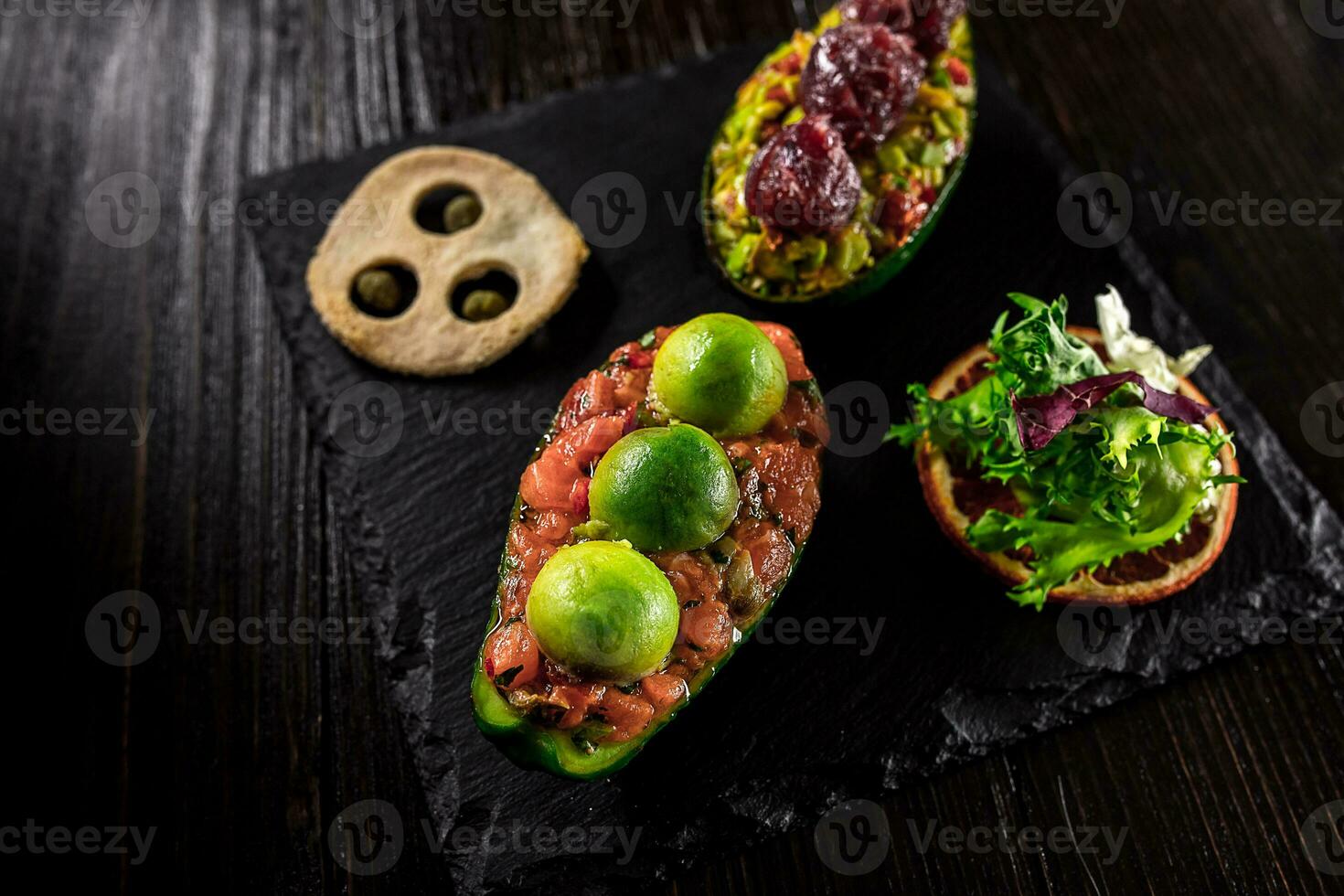 Salmon tartare and avocado salad on a black background photo