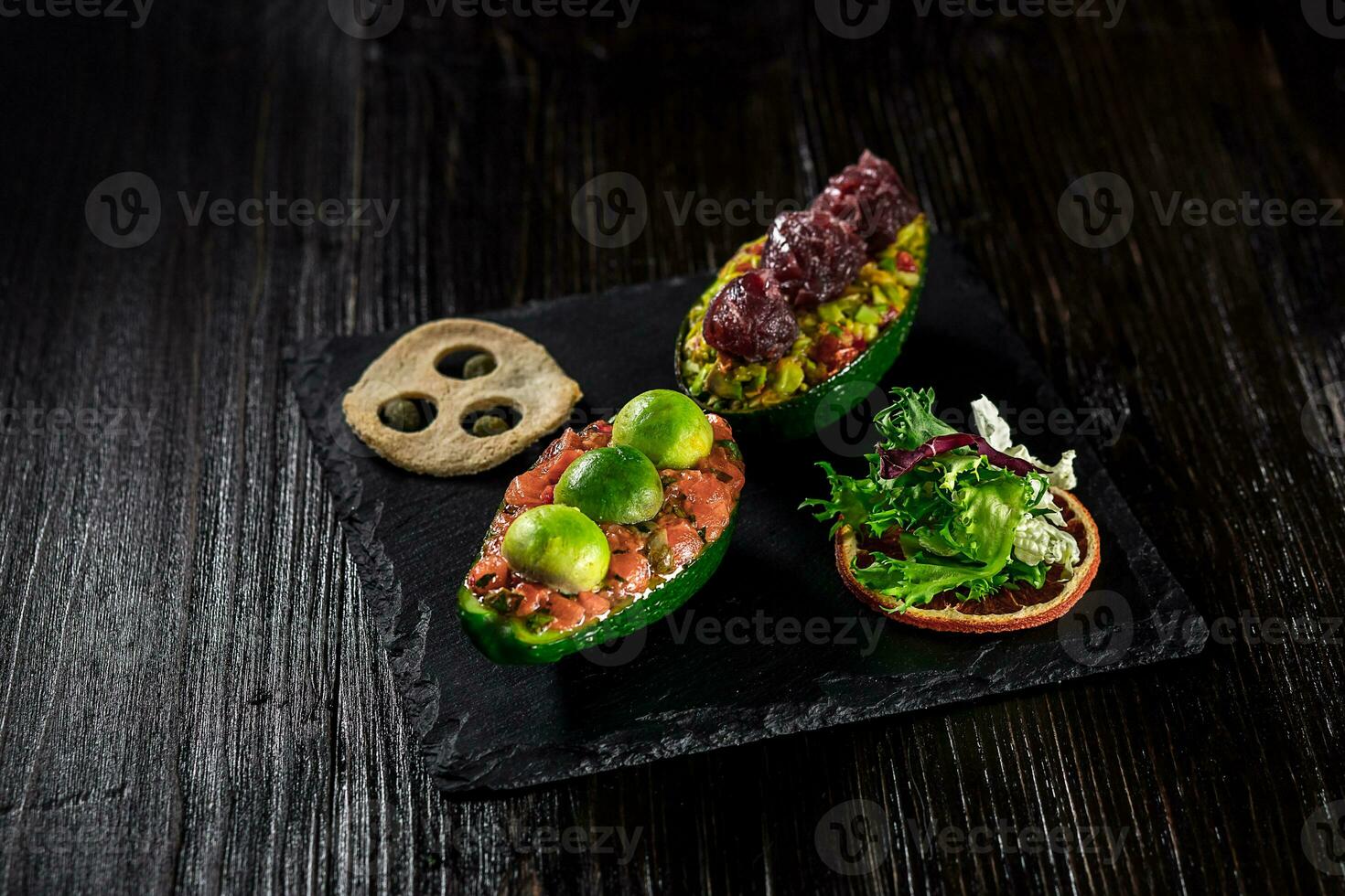 Salmon tartare and avocado salad on a black background photo