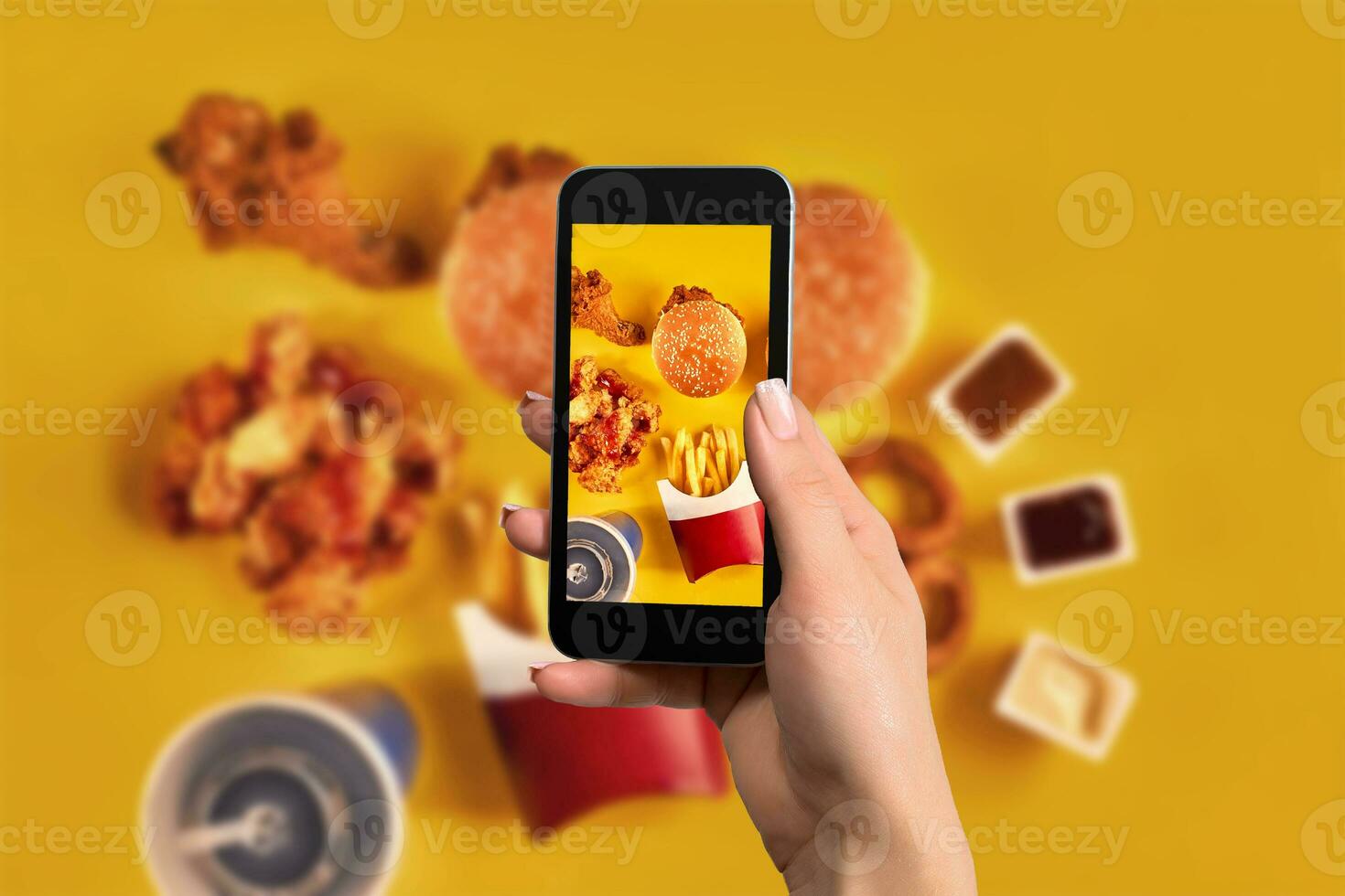 Female hands taking photo of tasty burger with snacks on table