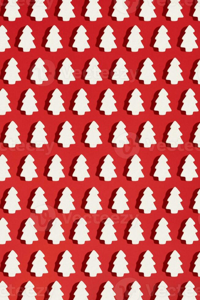 Pattern made of white christmas decoration with christmas tree on red background. Christmas wallpaper. photo