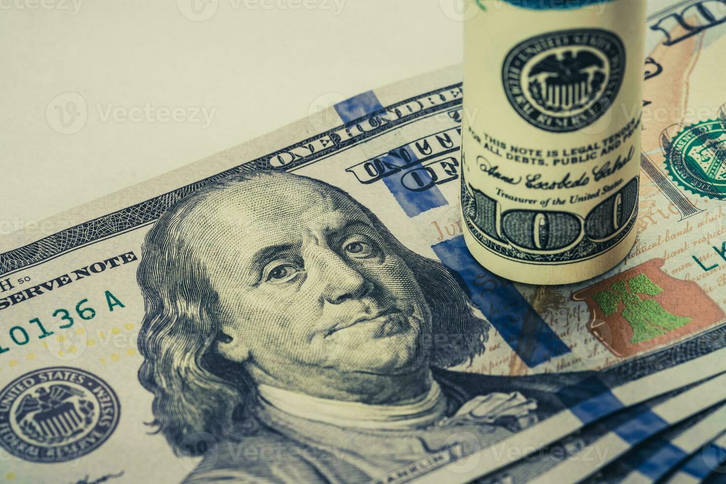 A coiled 100 dollar bill which rests on another angled 100 dollar bill isolated on white background photo