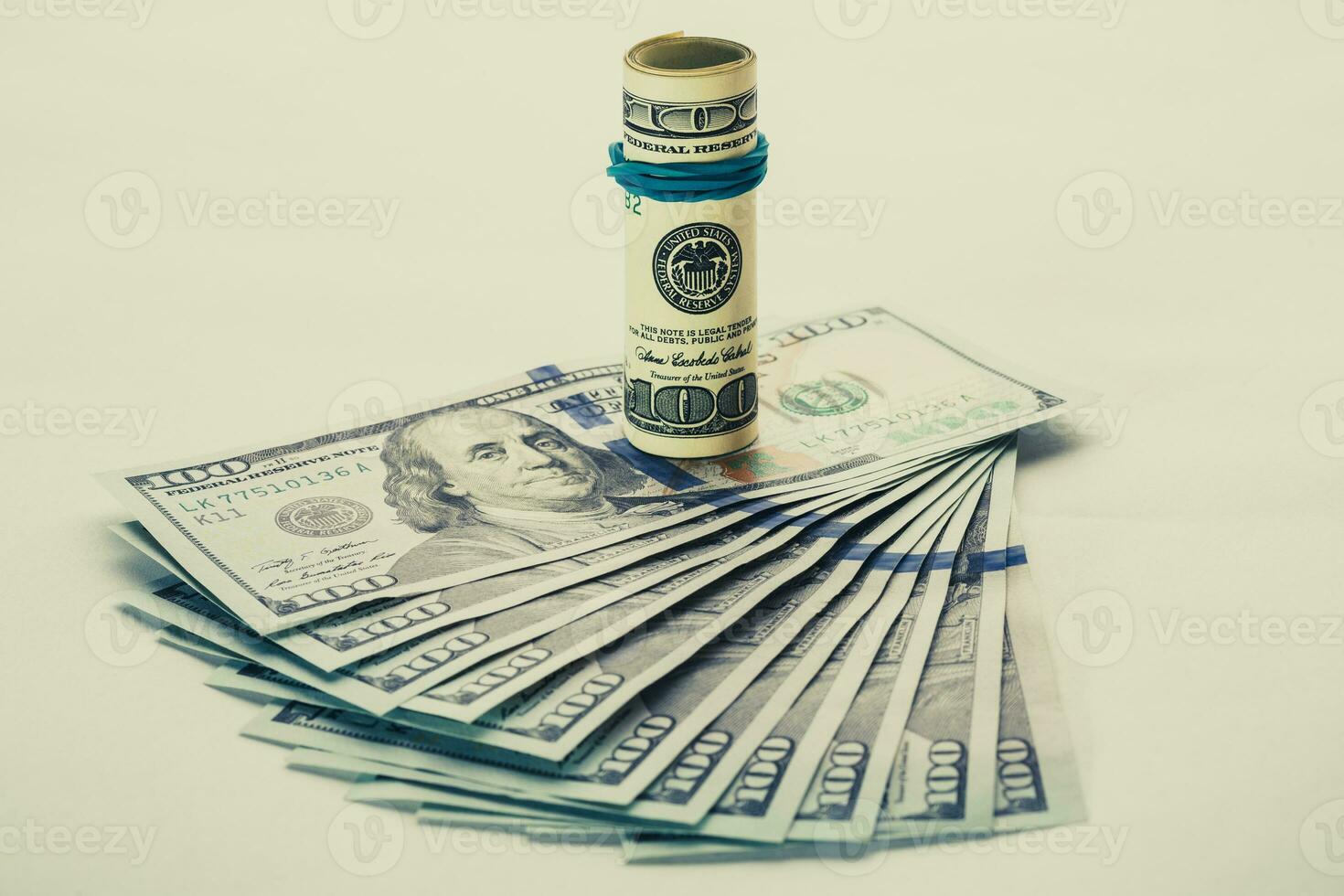 A coiled 100 dollar bill which rests on another angled 100 dollar bill isolated on white background photo