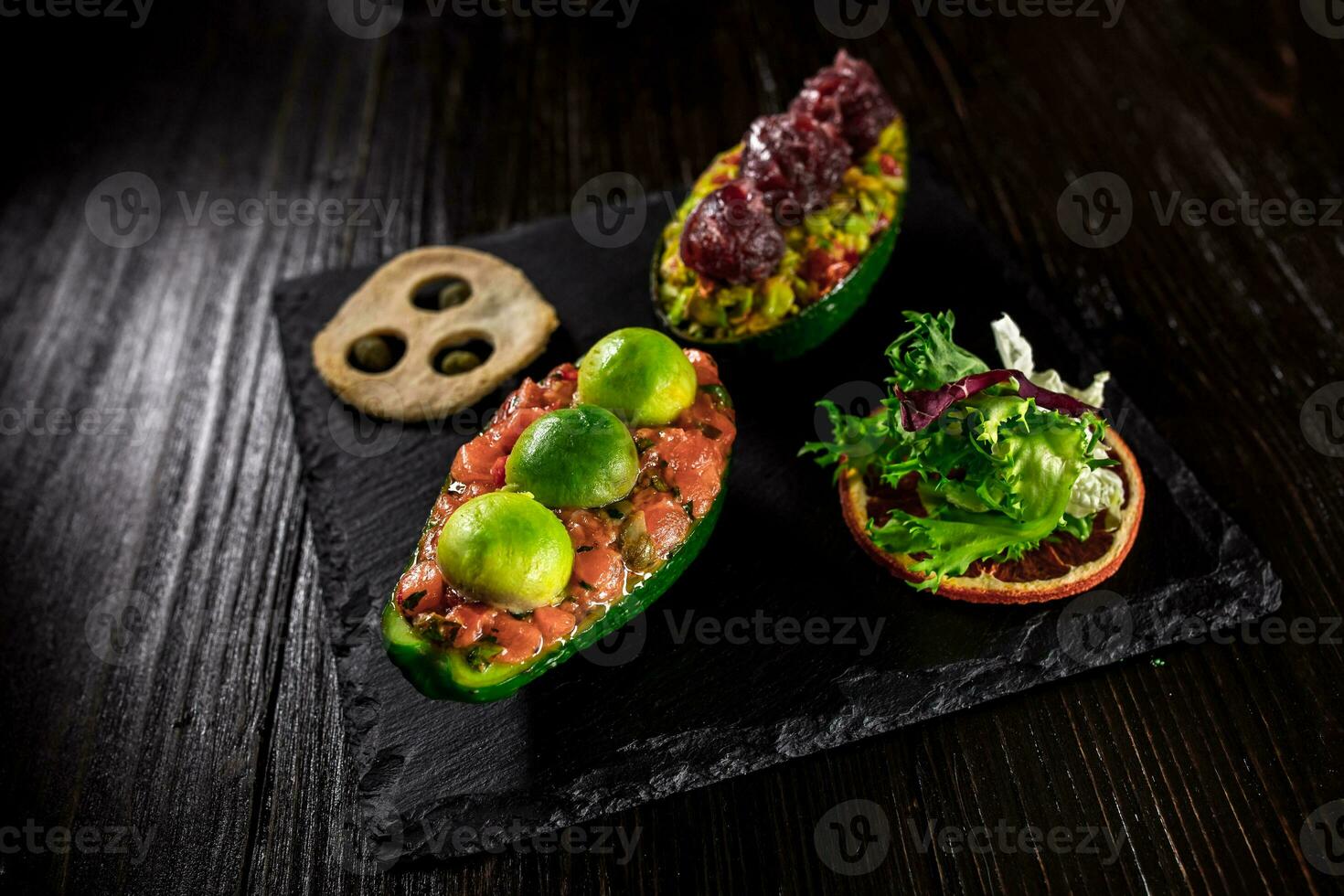 Salmon tartare and avocado salad on a black background photo