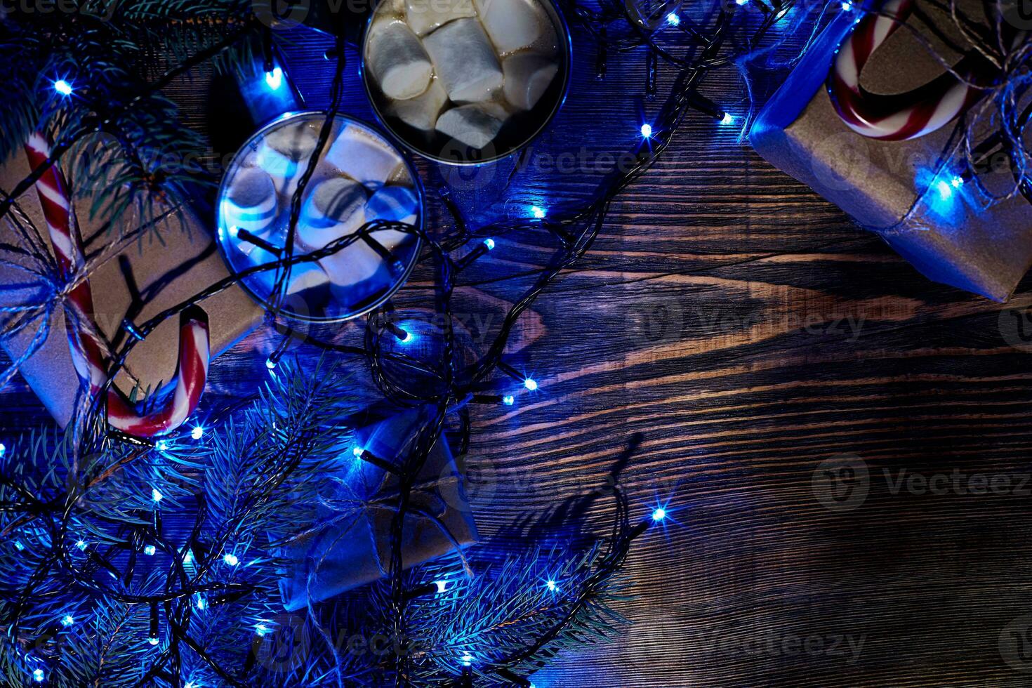 Christmas hot drink. Cocoa with marshmallow, garland and spruce branches on a wooden background. Top view photo