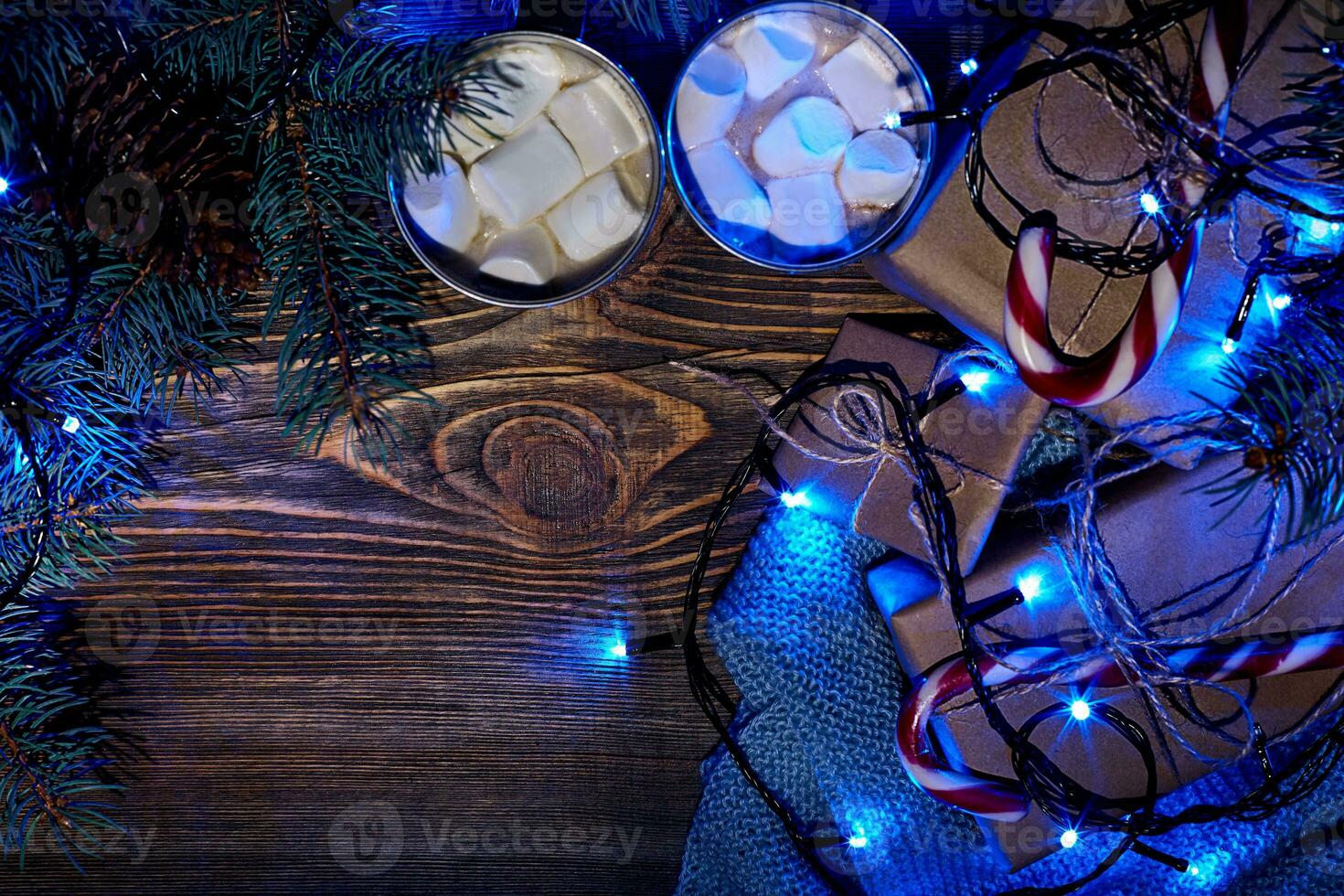 Christmas hot drink. Cocoa with marshmallow, garland and spruce branches on a wooden background. Top view photo