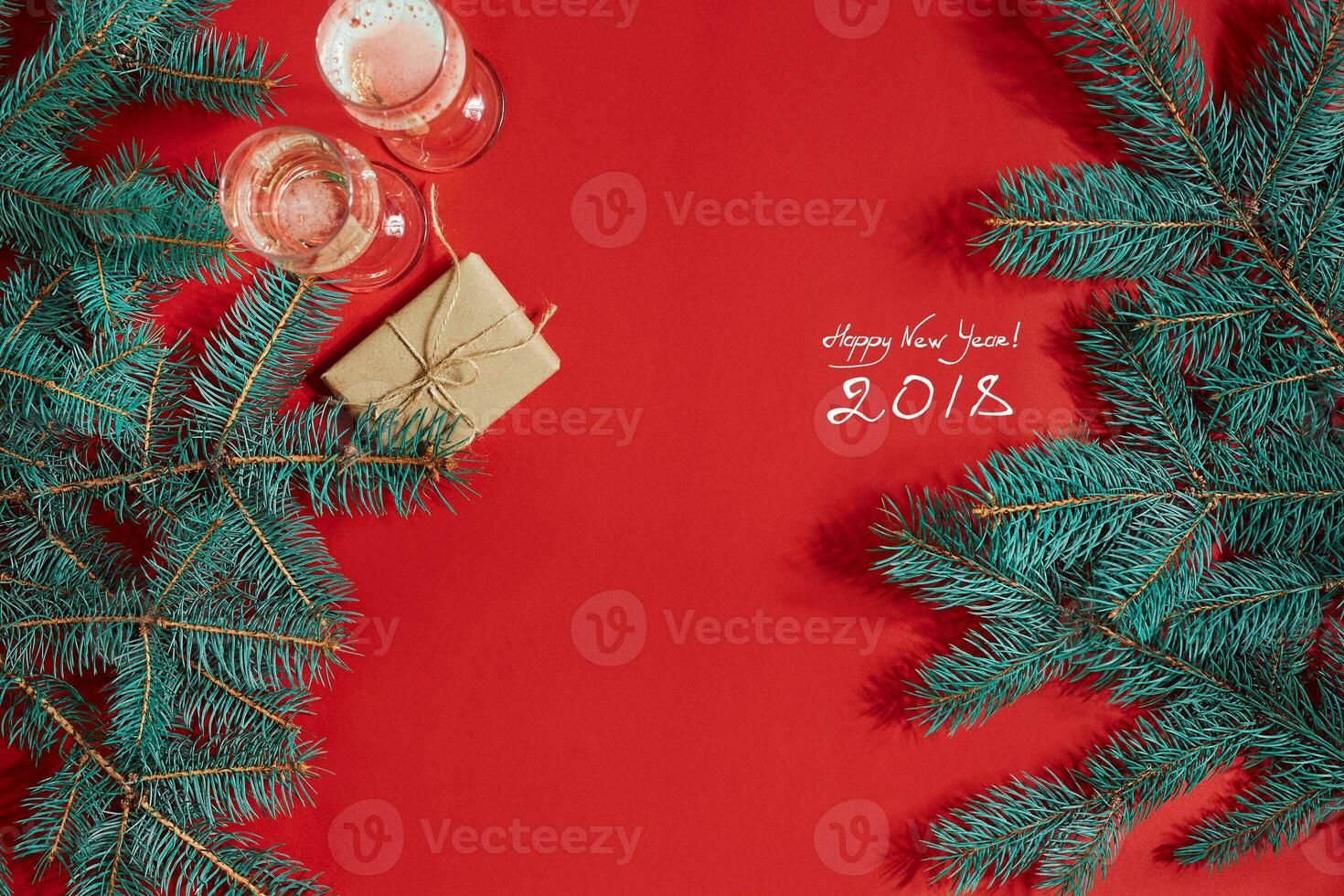 Two glasses of champagne with Christmas tree branch and small gift on a red background photo
