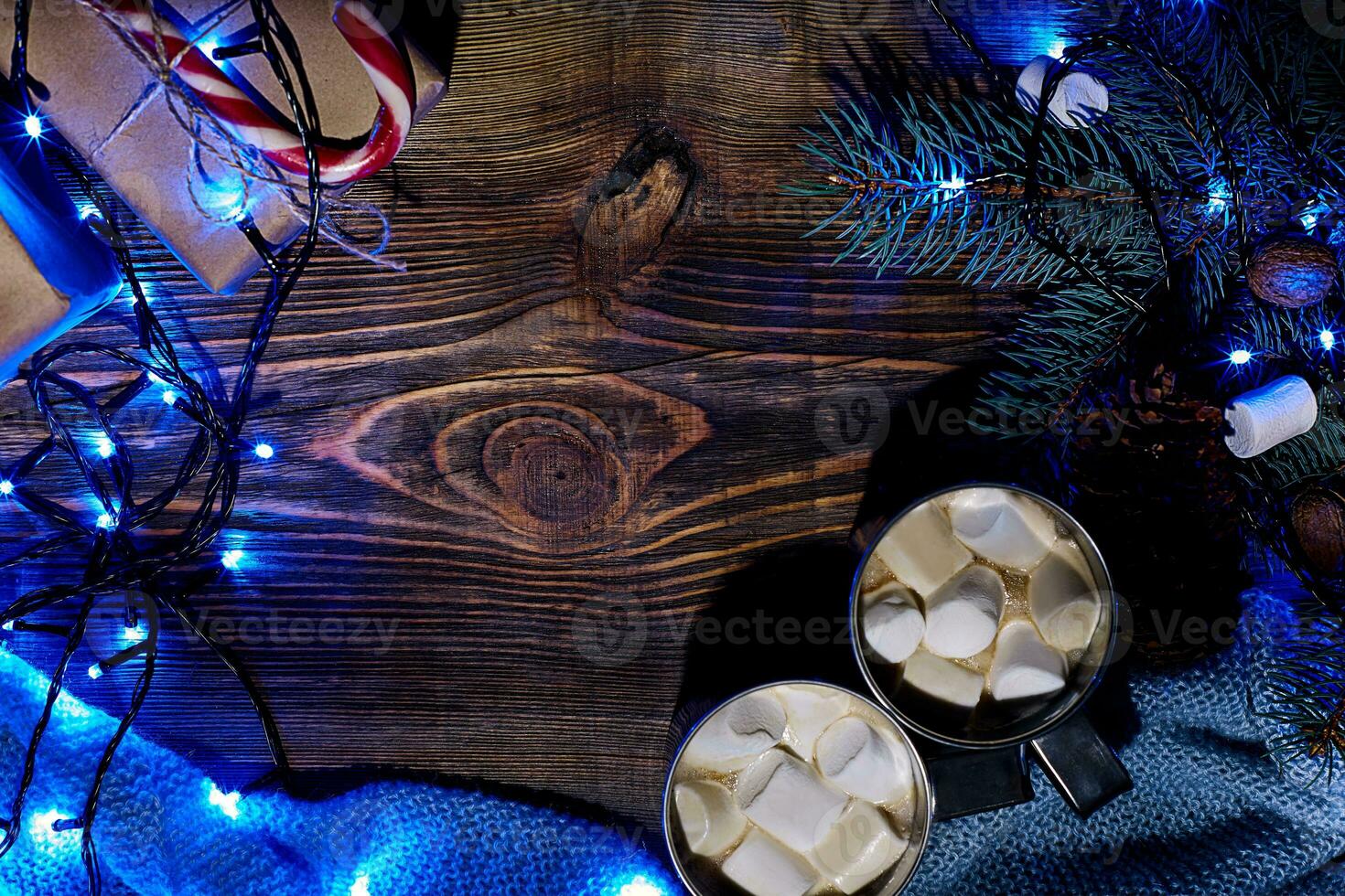 Christmas hot drink. Cocoa with marshmallow, garland and spruce branches on a wooden background. Top view photo