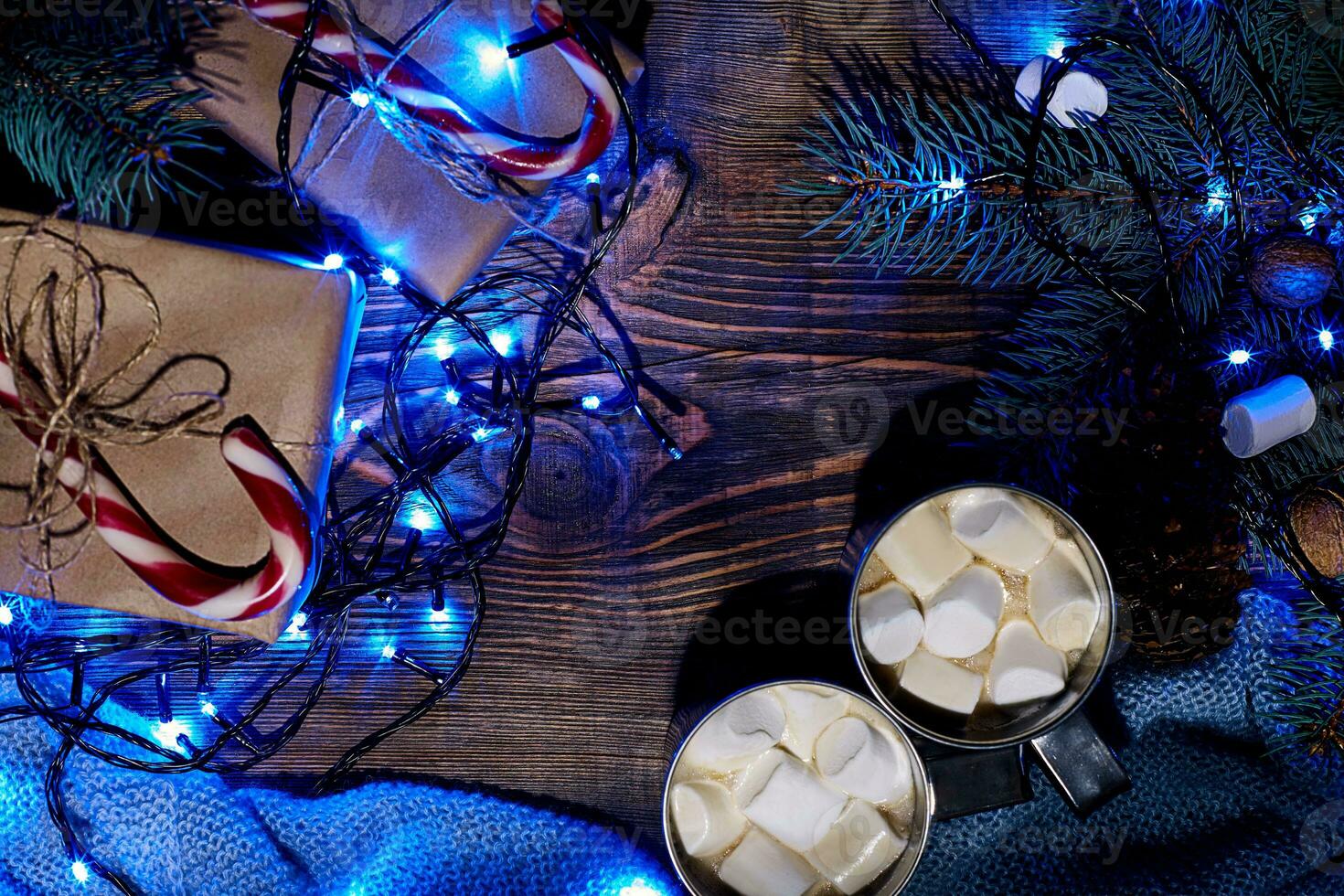 Christmas hot drink. Cocoa with marshmallow, garland and spruce branches on a wooden background. Top view photo