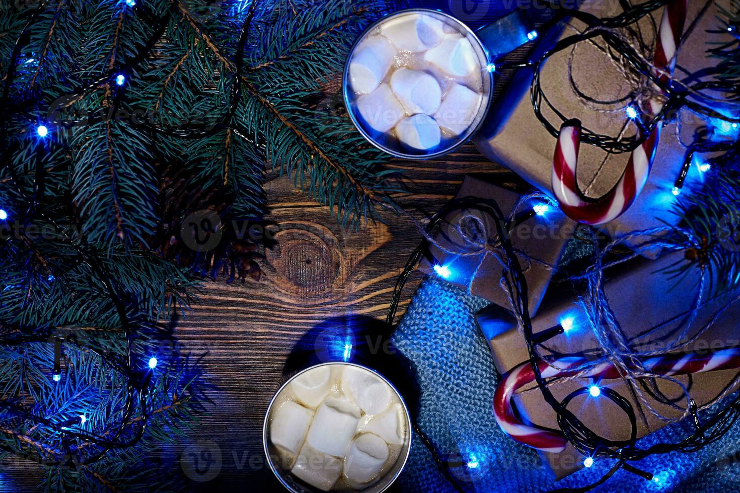 Christmas hot drink. Cocoa with marshmallow, garland and spruce branches on a wooden background. Top view photo