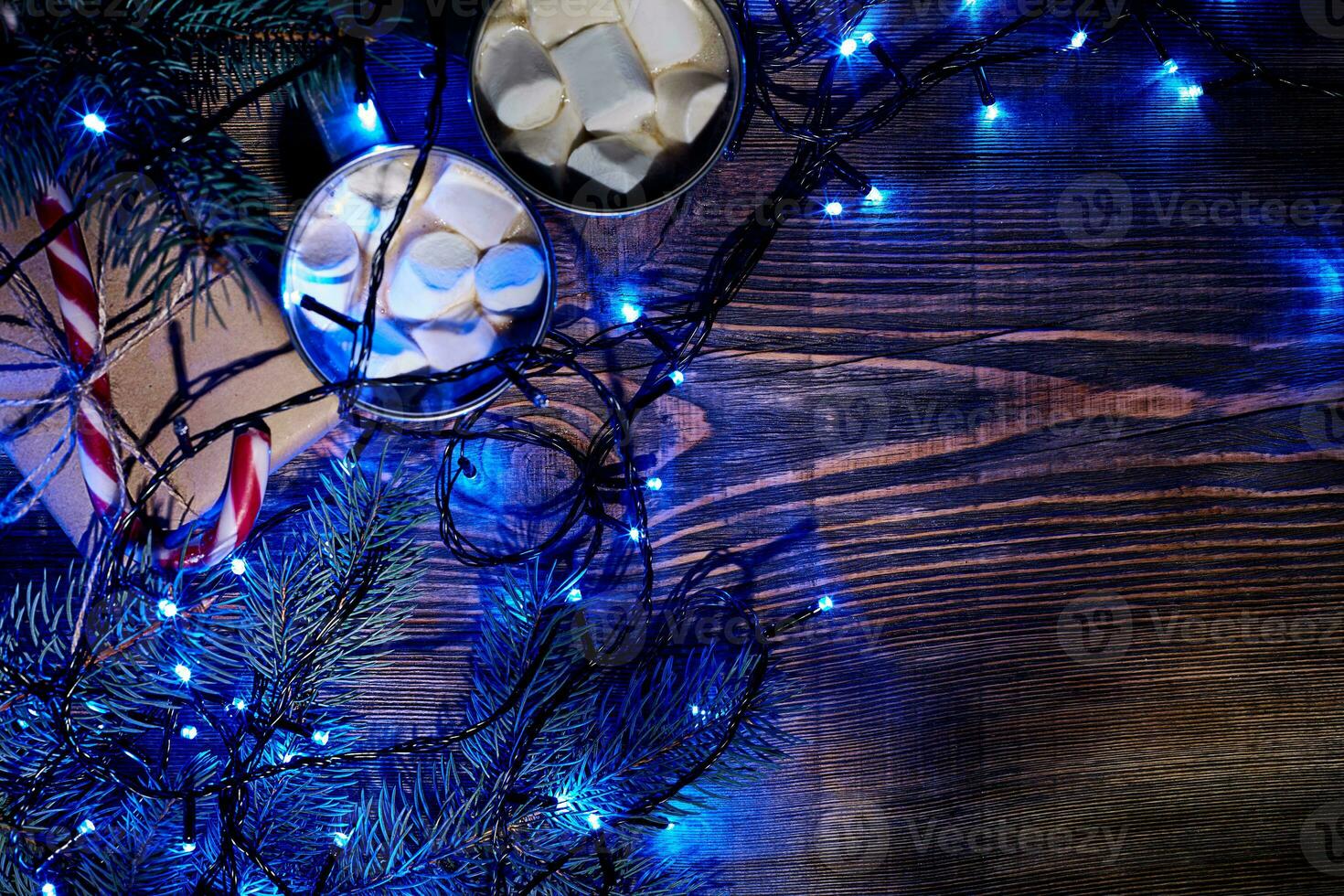 Christmas hot drink. Cocoa with marshmallow, garland and spruce branches on a wooden background. Top view photo
