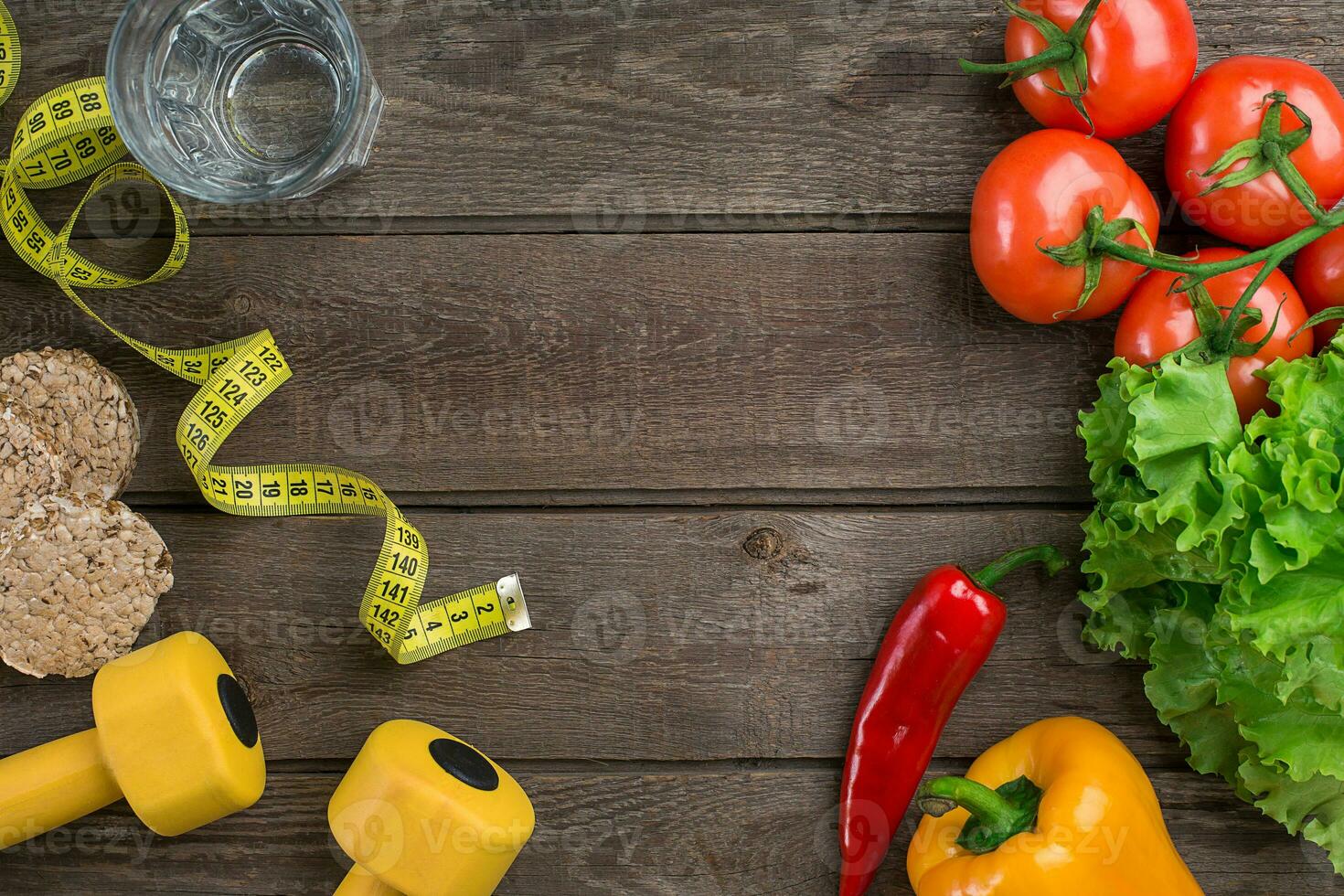 Sport and diet. Vegetables, dumbbells and centimeter. Peppers, tomatoes, salad on rustic background photo