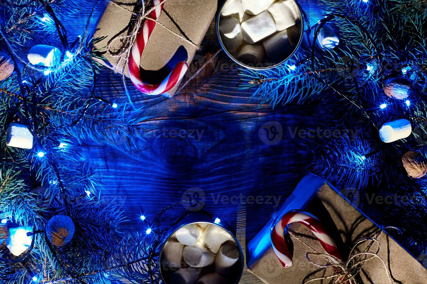 Christmas hot drink. Cocoa with marshmallow, garland and spruce branches on a wooden background. Top view photo