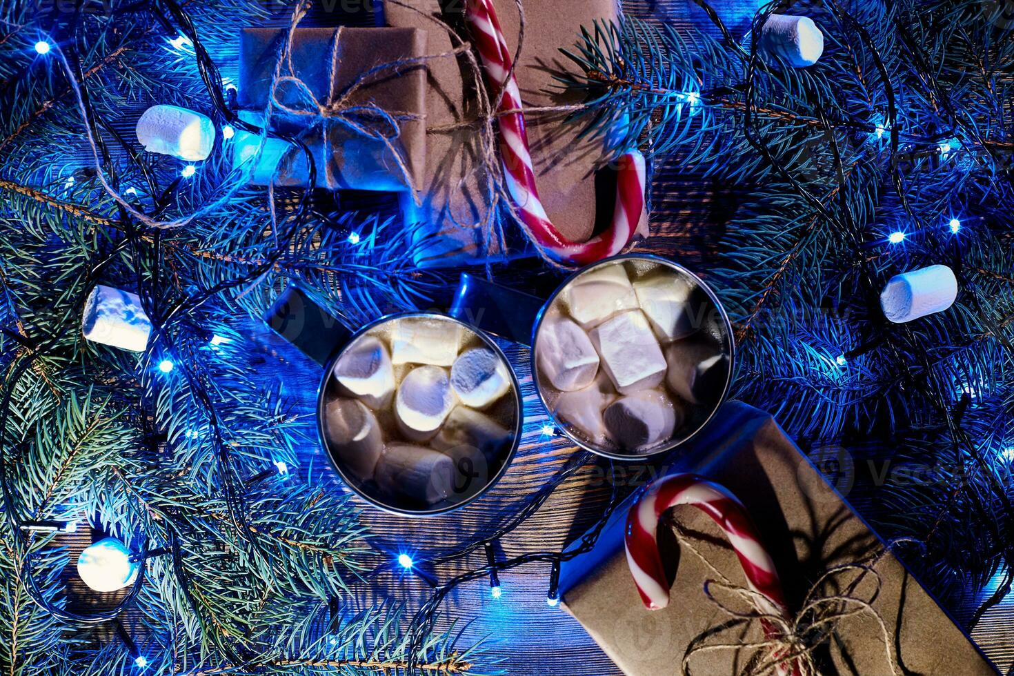 Christmas hot drink. Cocoa with marshmallow, garland and spruce branches on a wooden background. Top view photo
