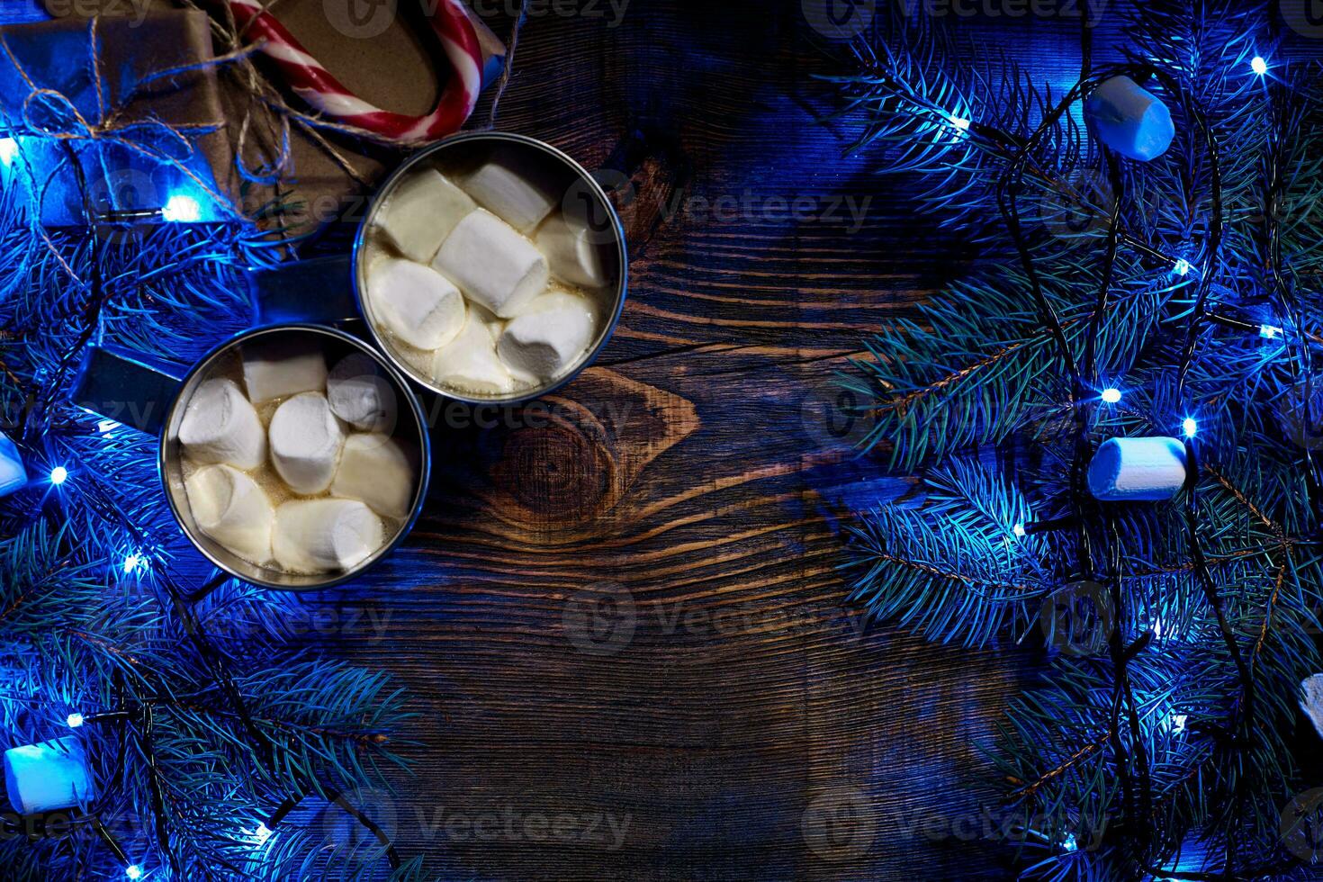 Christmas hot drink. Cocoa with marshmallow, garland and spruce branches on a wooden background. Top view photo
