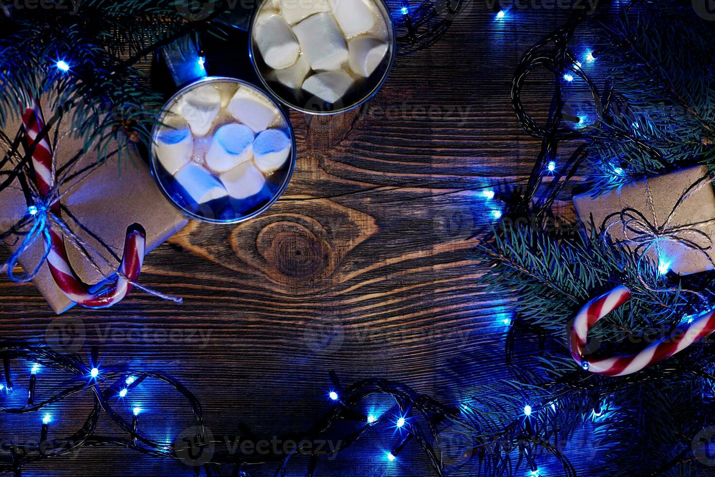Christmas hot drink. Cocoa with marshmallow, garland and spruce branches on a wooden background. Top view photo