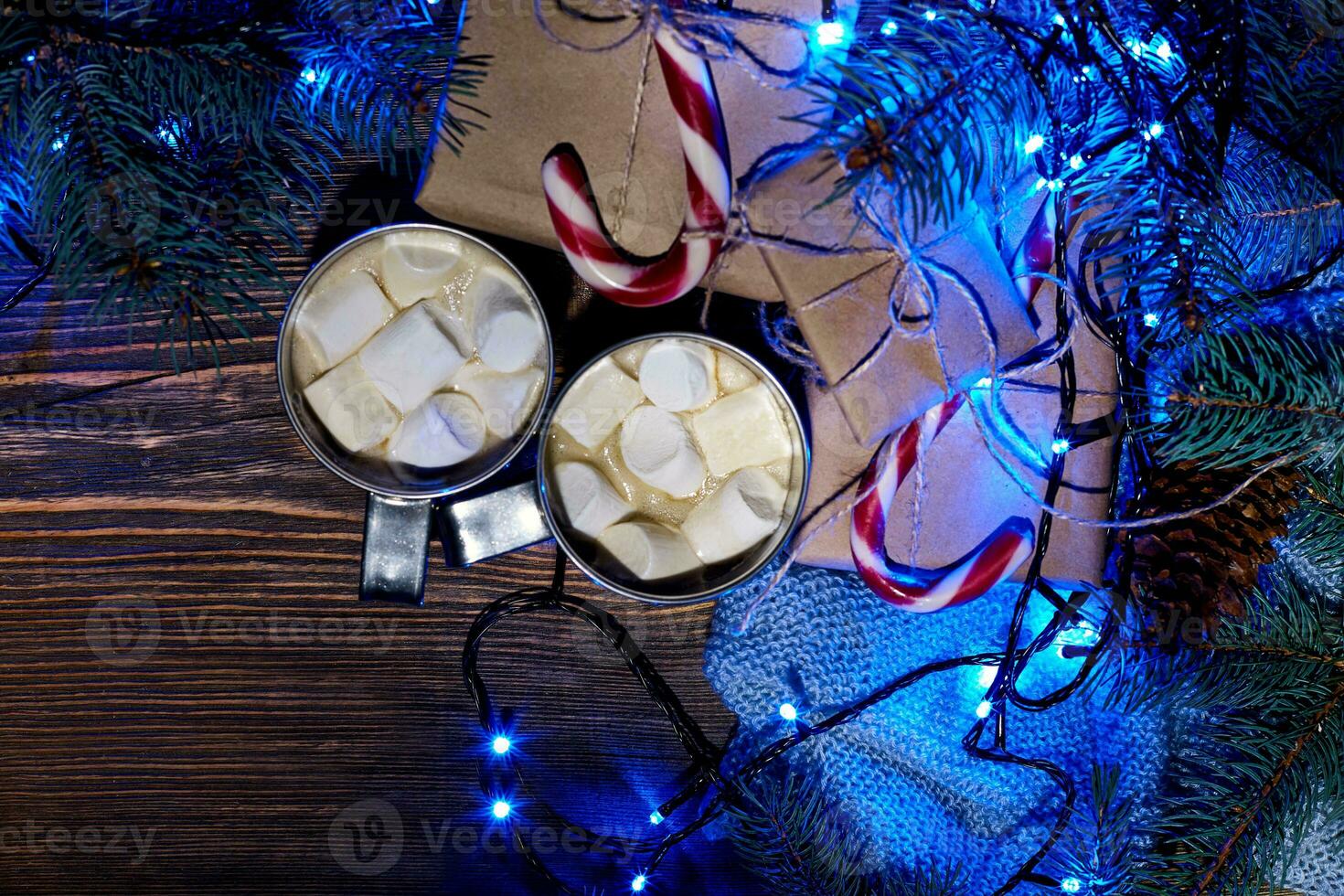 Christmas hot drink. Cocoa with marshmallow, garland and spruce branches on a wooden background. Top view photo