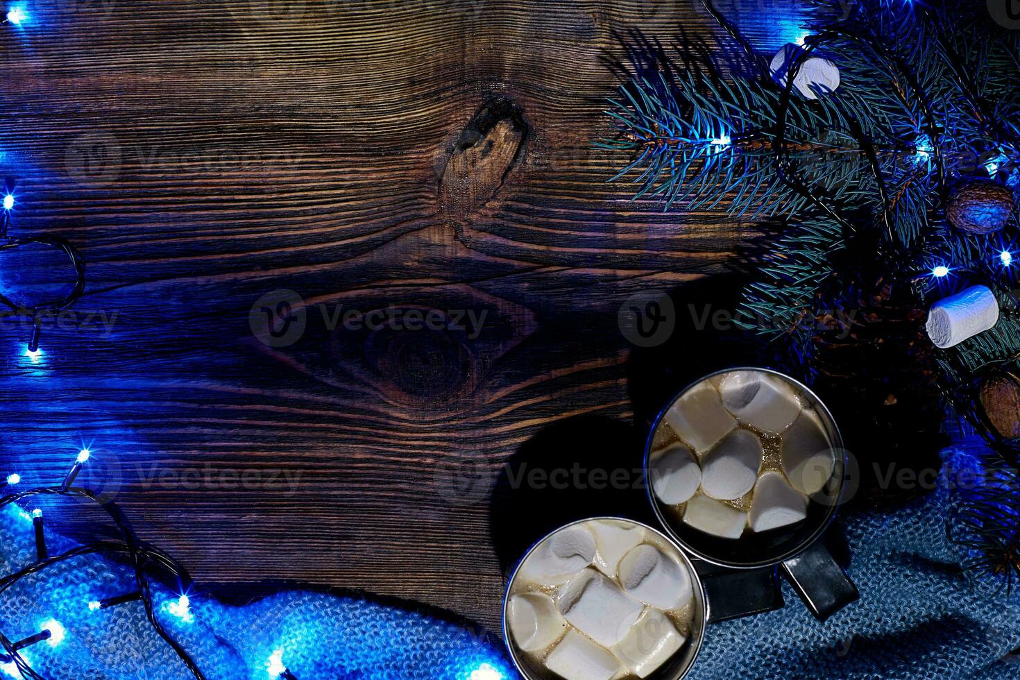 Christmas hot drink. Cocoa with marshmallow, garland and spruce branches on a wooden background. Top view photo