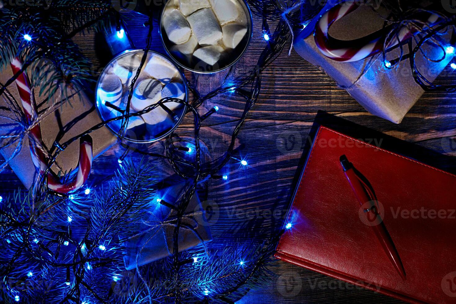 Christmas hot drink. Cocoa with marshmallow, garland and spruce branches on a wooden background. Top view photo