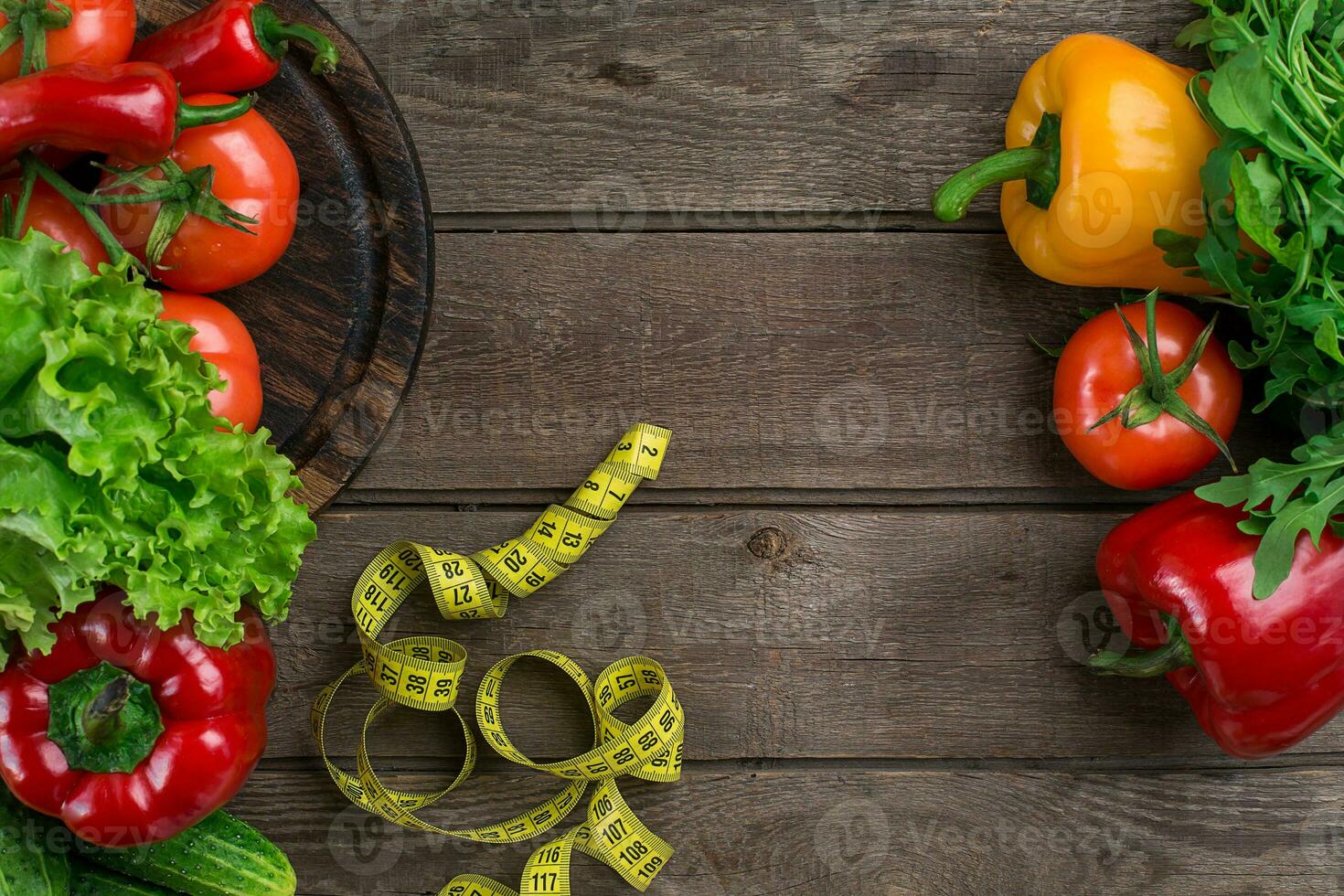 Vegetables and in measure tape in diet on wooden background. Top view. photo