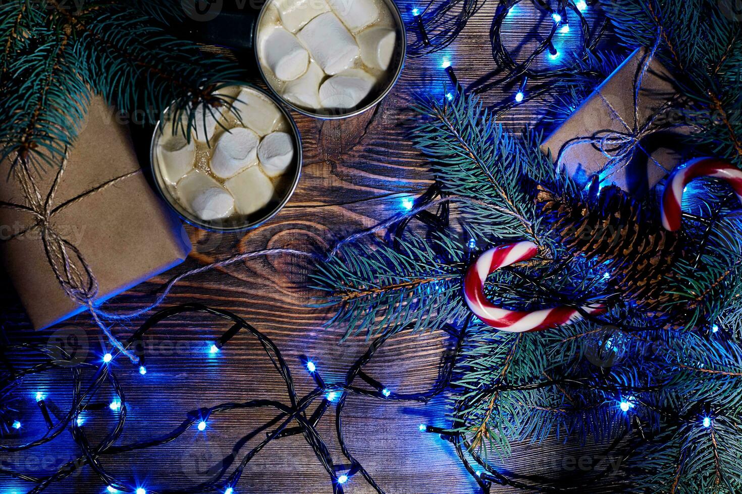 Christmas hot drink. Cocoa with marshmallow, garland and spruce branches on a wooden background. Top view photo