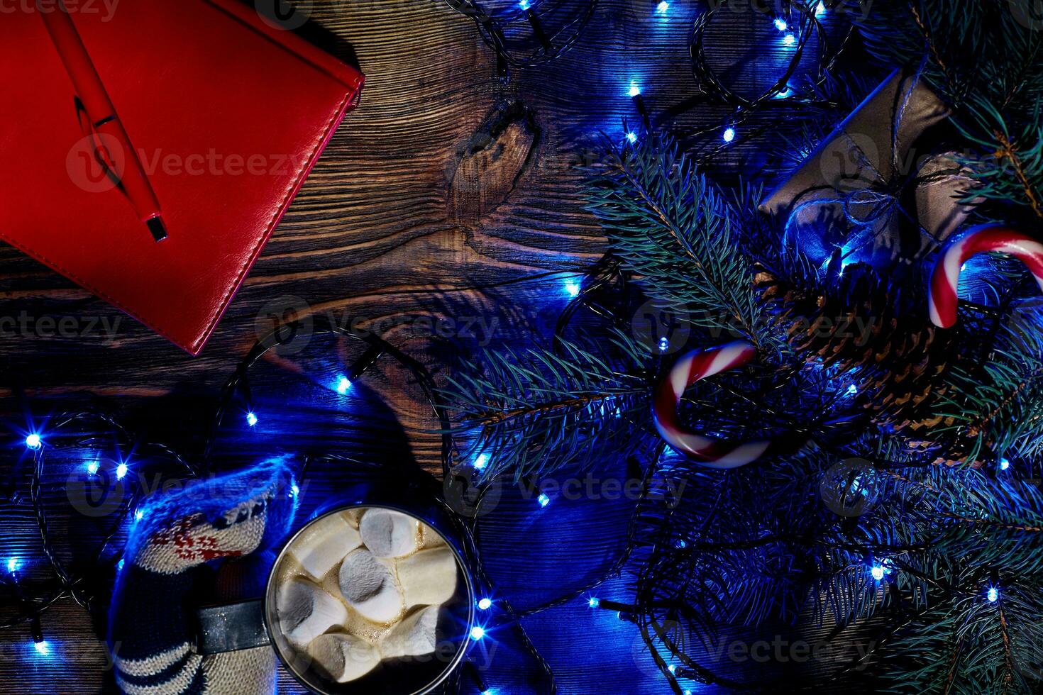 Christmas hot drink. Cocoa with marshmallow, garland and spruce branches on a wooden background. Top view photo