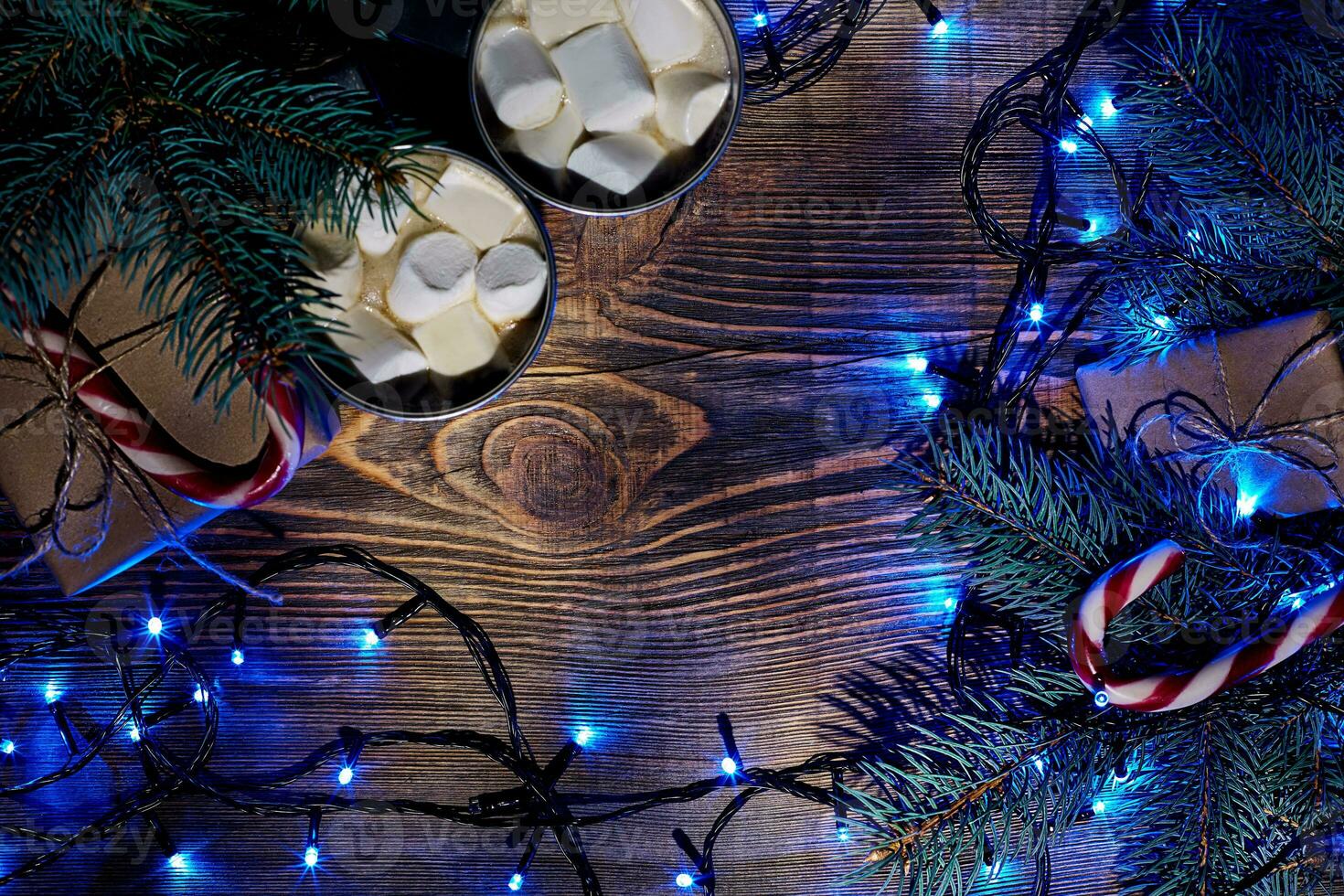 Christmas hot drink. Cocoa with marshmallow, garland and spruce branches on a wooden background. Top view photo