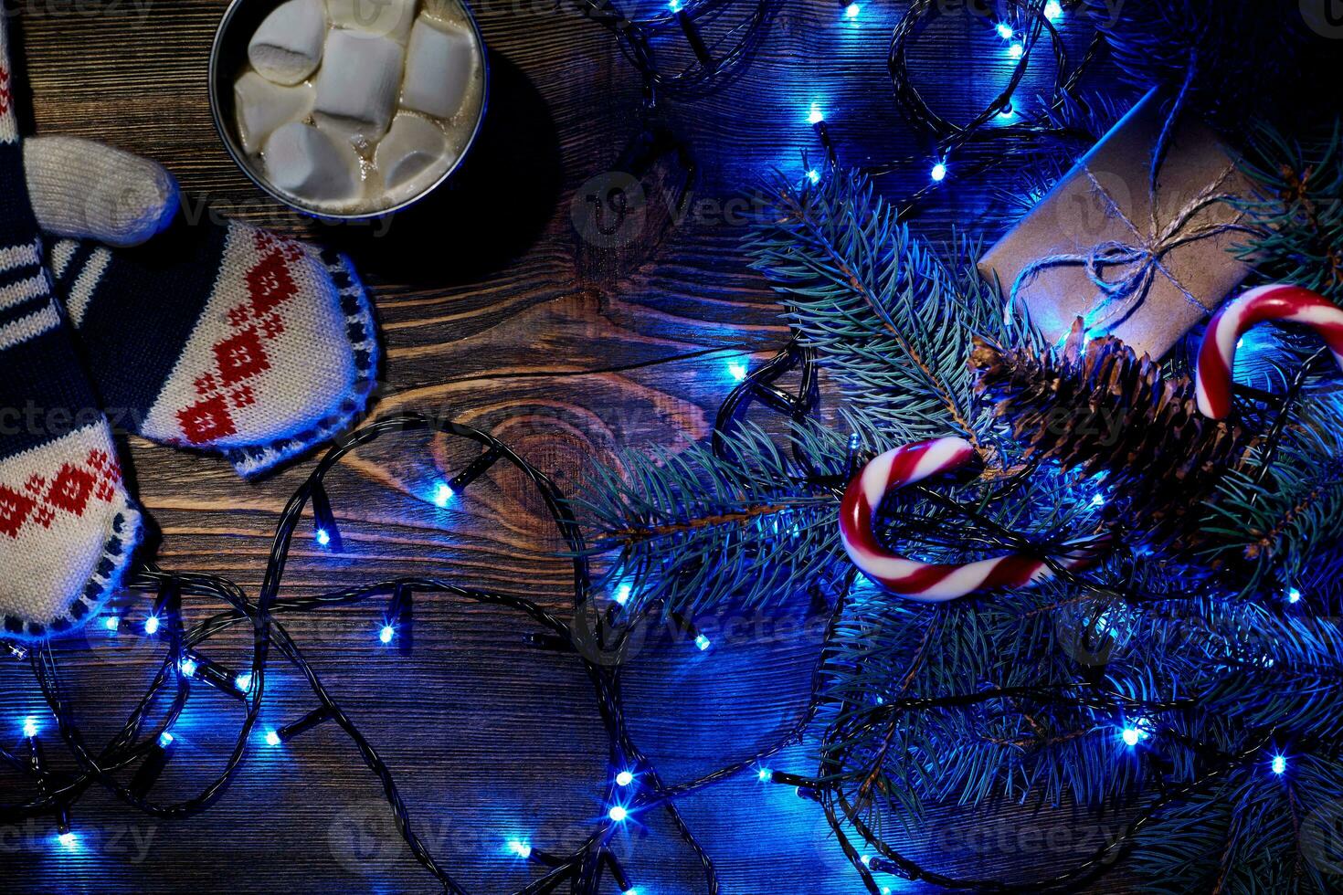 Christmas hot drink. Cocoa with marshmallow, garland and spruce branches on a wooden background. Top view photo